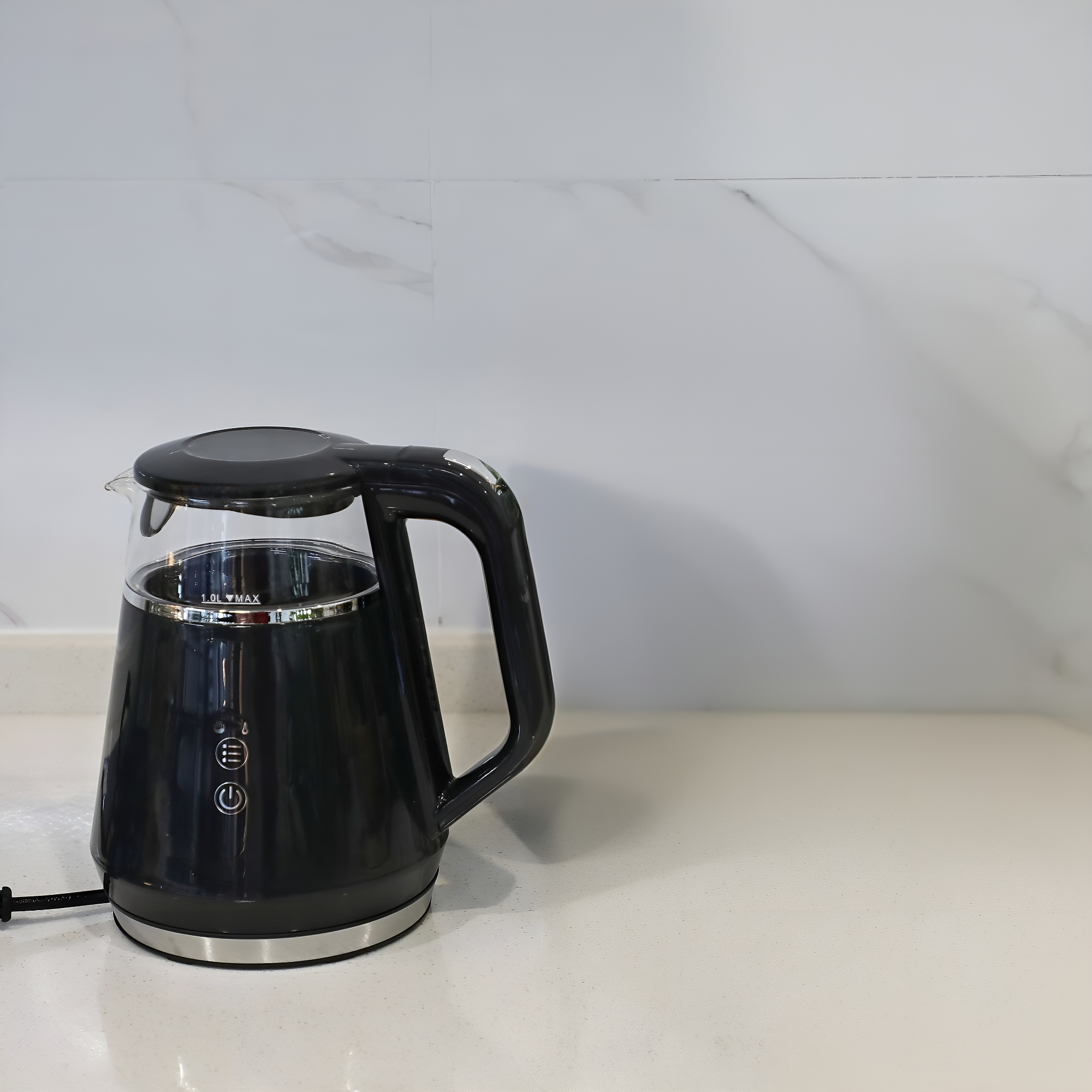 Schwarzer elektrischer Wasserkocher auf einer weißen Arbeitsplatte, mit einer weiß gefliesten Wand im Hintergrund.