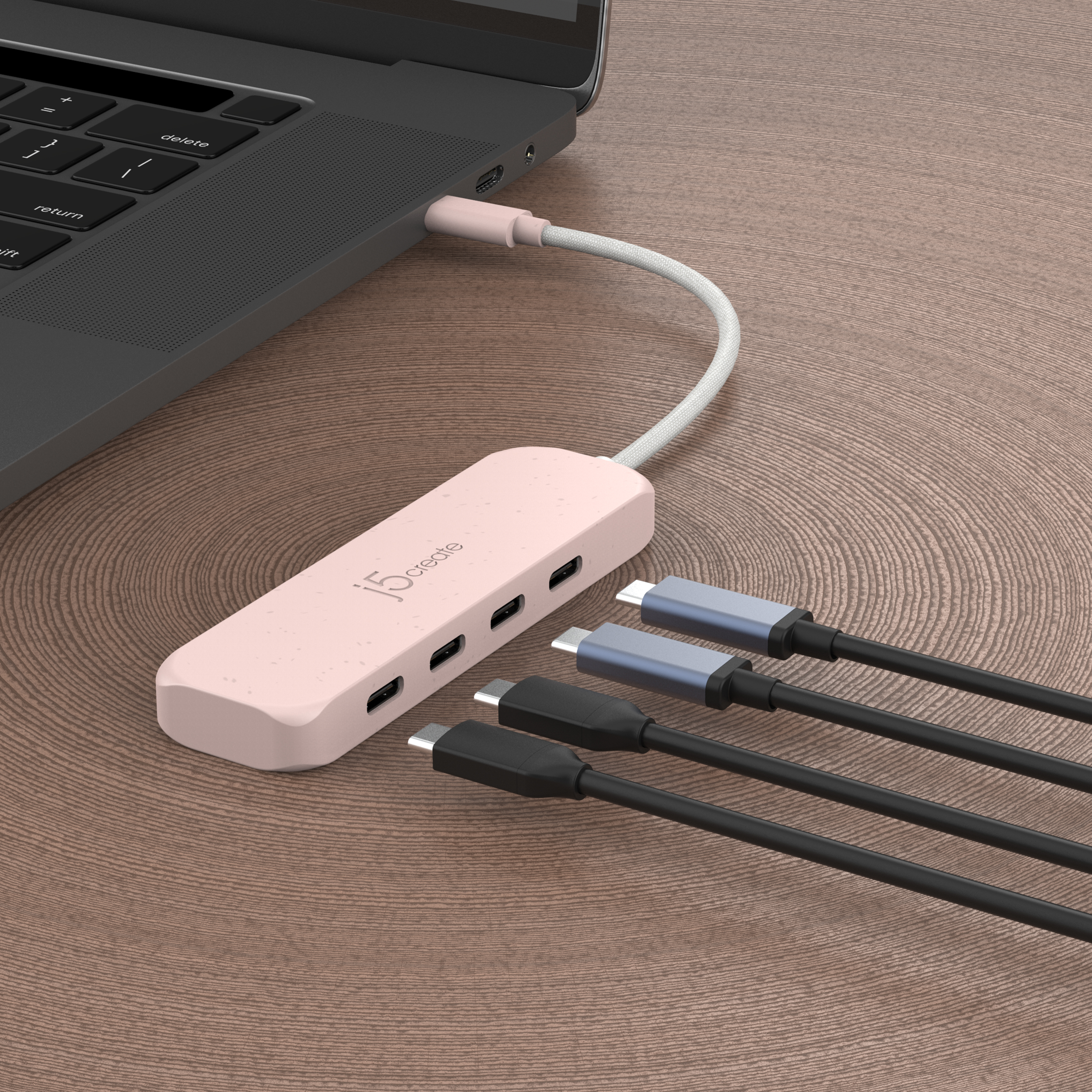 Un hub rosa con puertos USB conectado a un portátil con cables de carga.