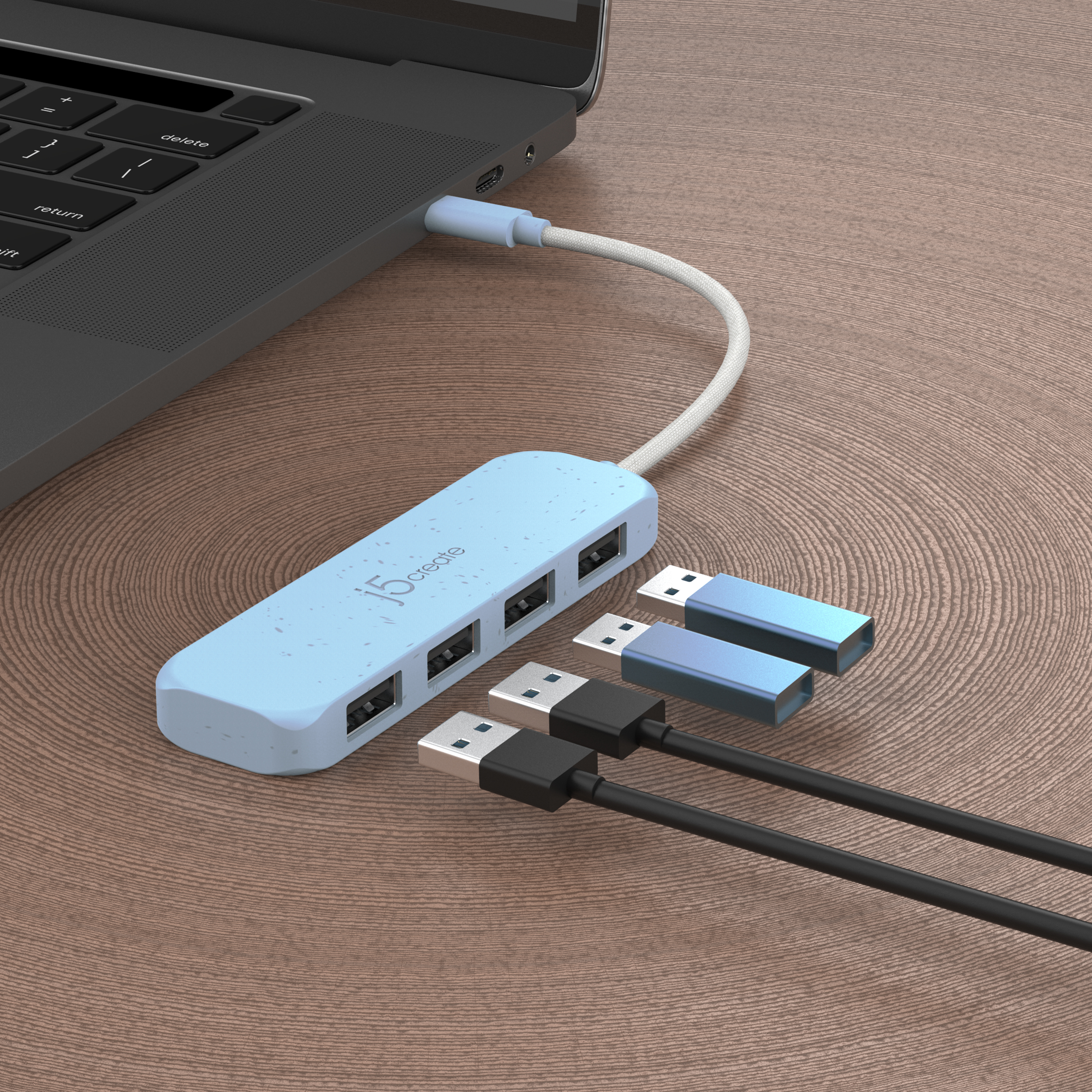 Laptop, verbunden mit einem blauen USB-Hub mit drei USB-Steckern und zwei USB-Laufwerken auf Holz.