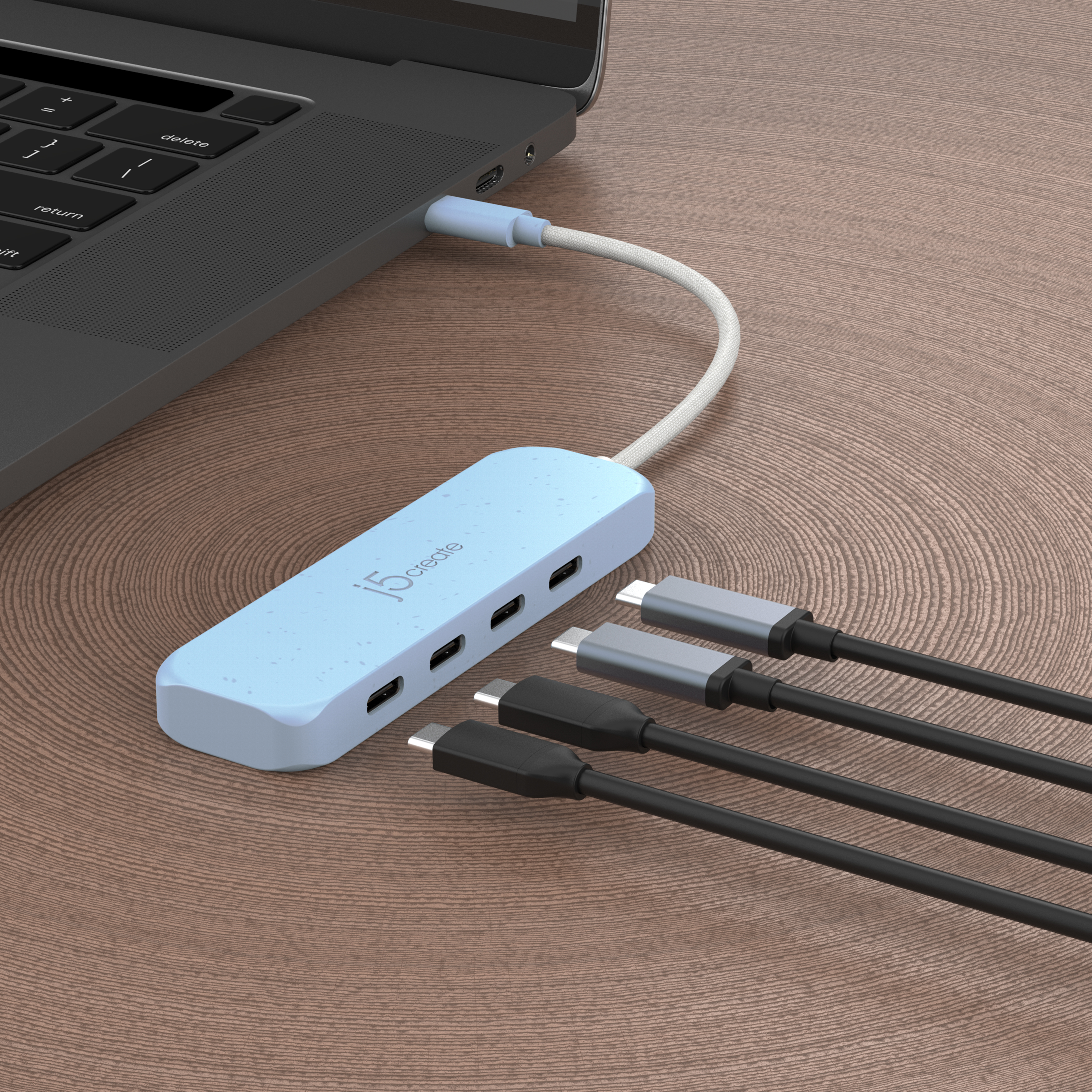 Hub USB bleu connecté à un ordinateur portable, trois câbles noirs sur bois.