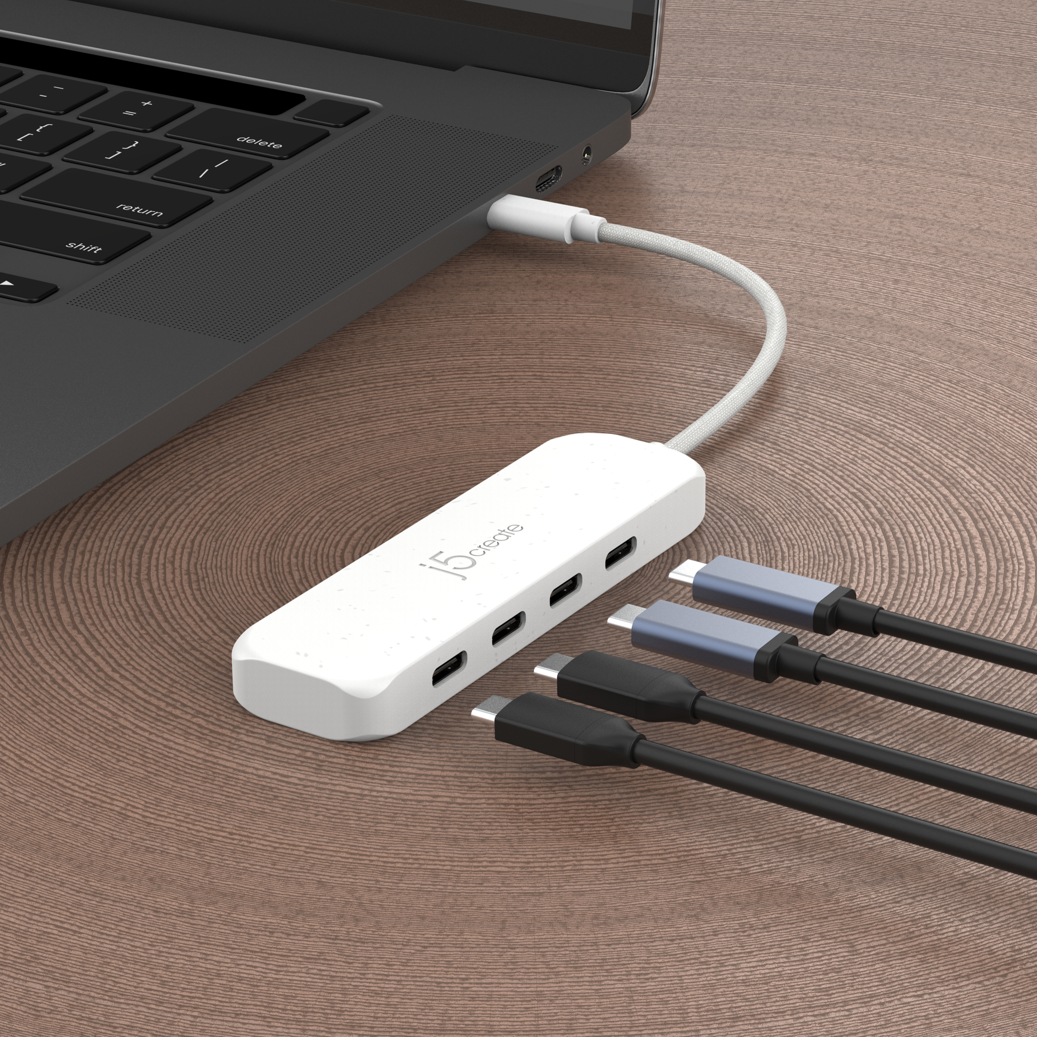 Weißer USB-C-Hub an Laptop angeschlossen, mit mehreren USB-C-Kabeln.