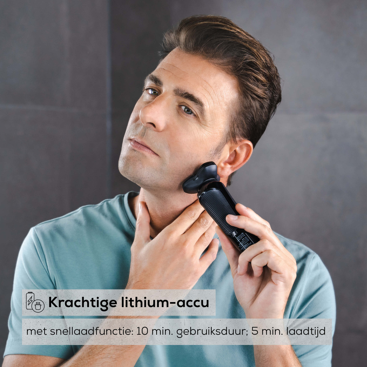 Homme se rasant le visage avec un rasoir électrique noir. Fond gris.