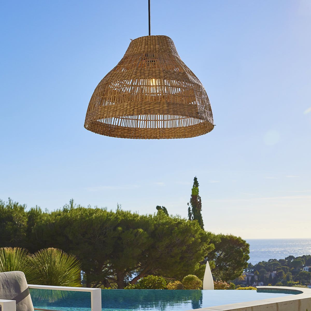 Rattan-Lampenschirm über einem Pool hängend.