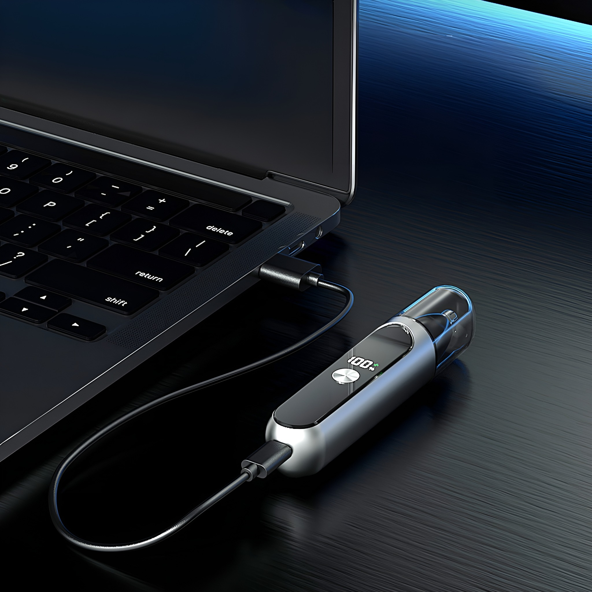 Laptop mit angeschlossenem Ladegerät. Das Gerät ist silberfarben und zeigt 100%. Kabel verbindet die beiden.