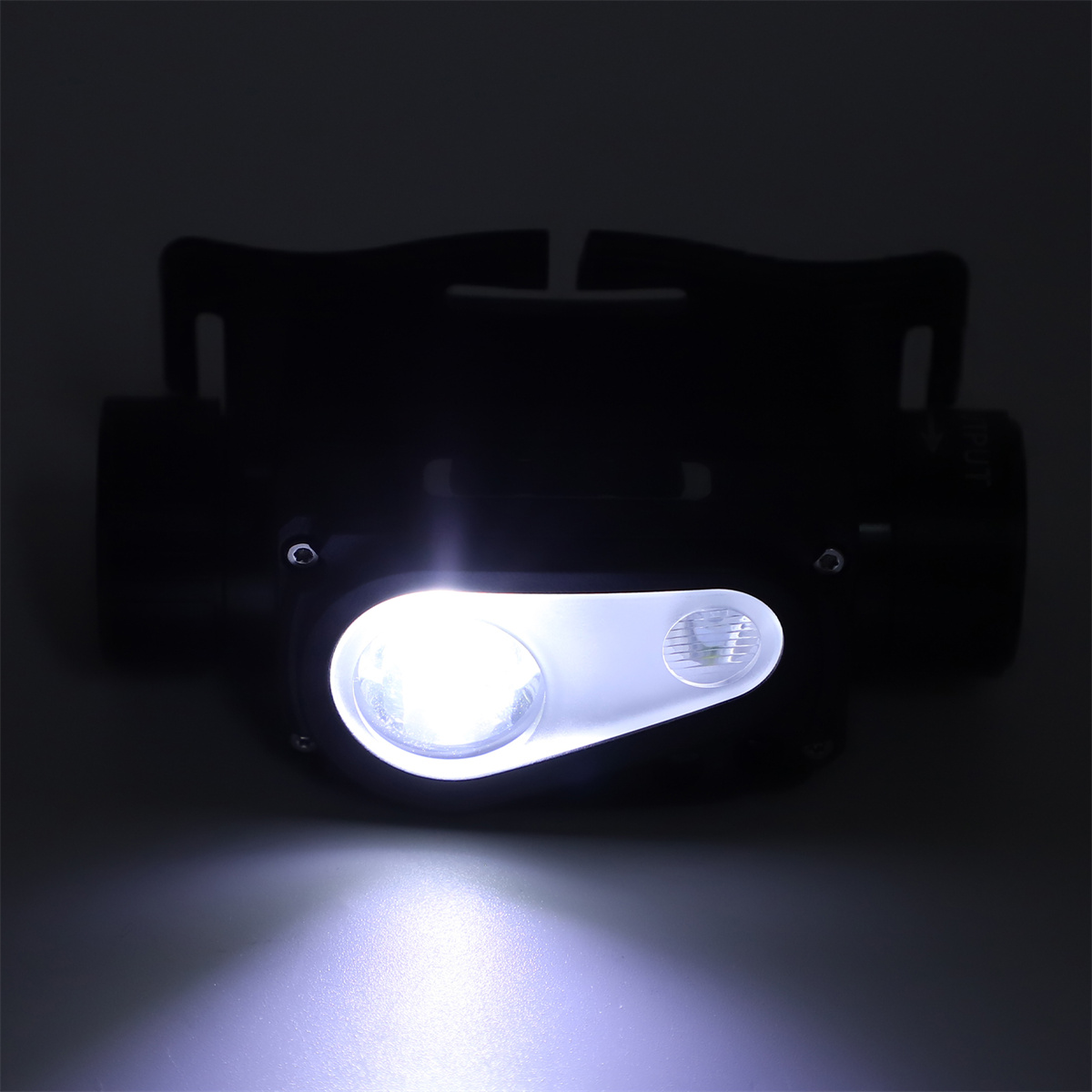 Eine Stirnlampe mit hellem weißem Licht auf einem schwarzen Rahmen, nach oben gerichtet, dunkler Hintergrund.