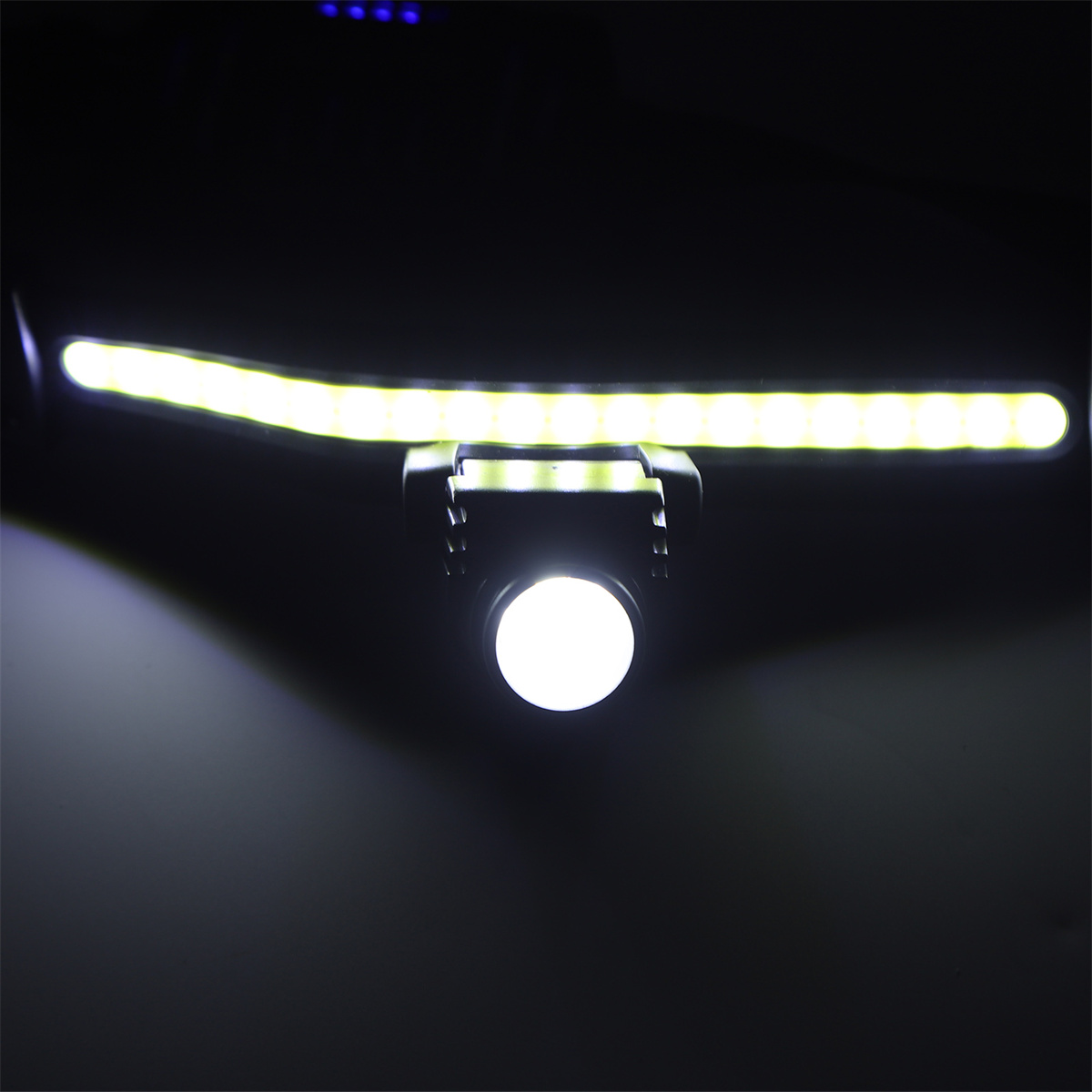 Nahaufnahme einer LED-Lichtleiste und eines Scheinwerfers, die einen dunklen Bereich beleuchten.
