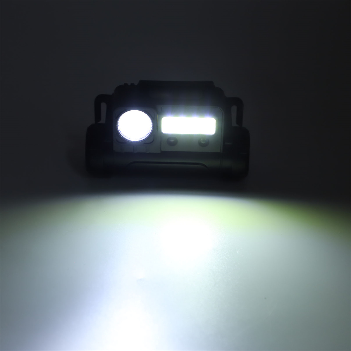 Schwarze Taschenlampe mit hellen weißen und grünen Lichtern auf dunklem Hintergrund.