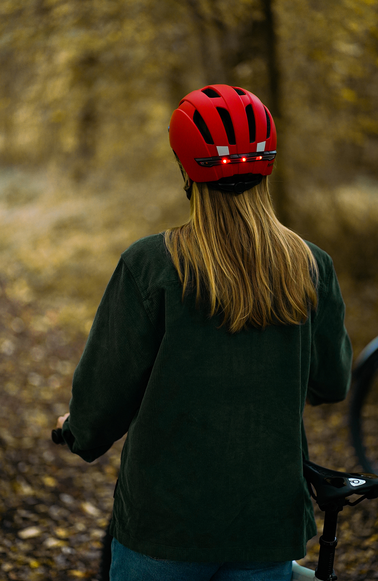 Eine Person mit rotem Helm und grüner Cordjacke in einer Waldumgebung.