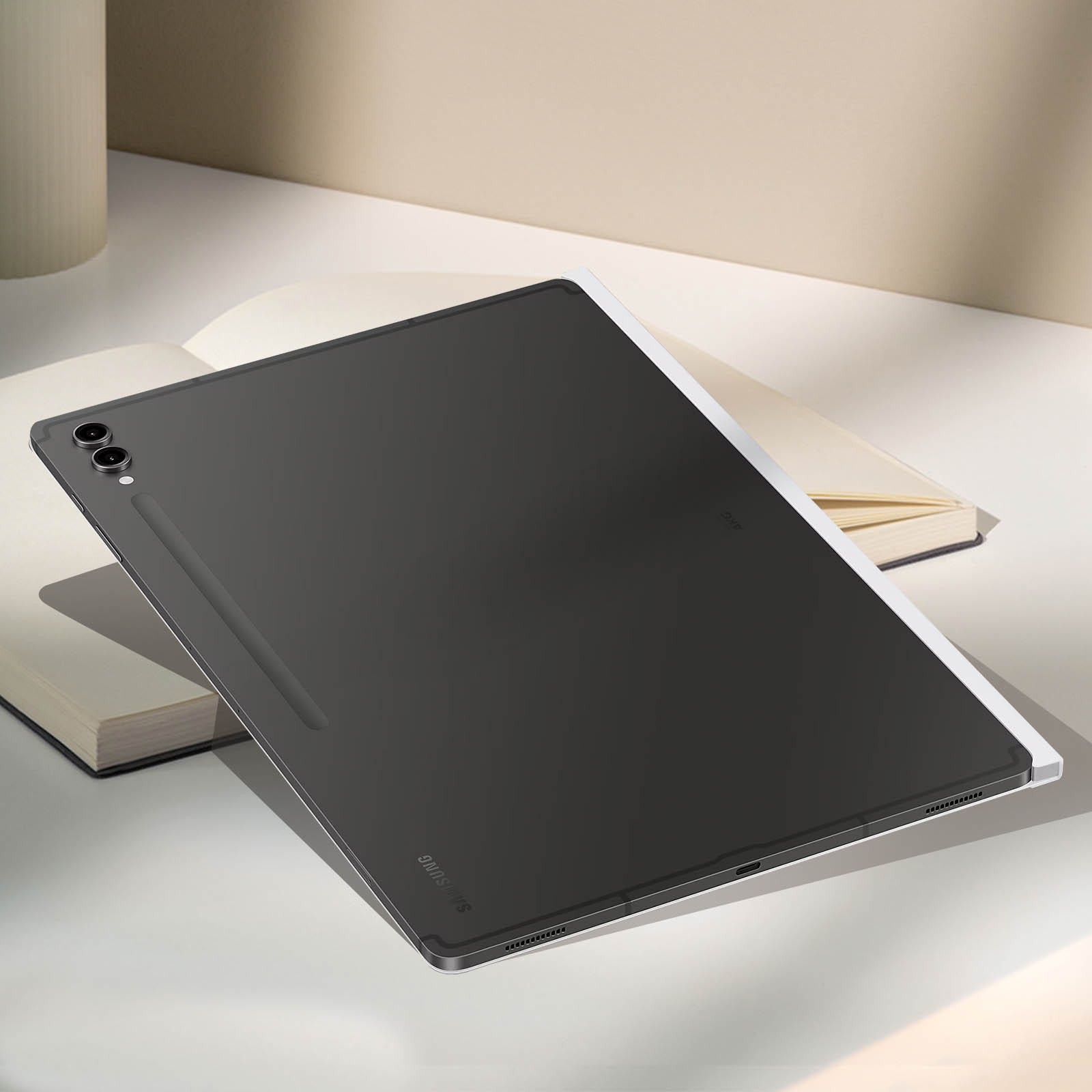 Tablet nero con penna, appoggiato su una superficie bianca sopra un libro aperto. Logo Samsung visibile.