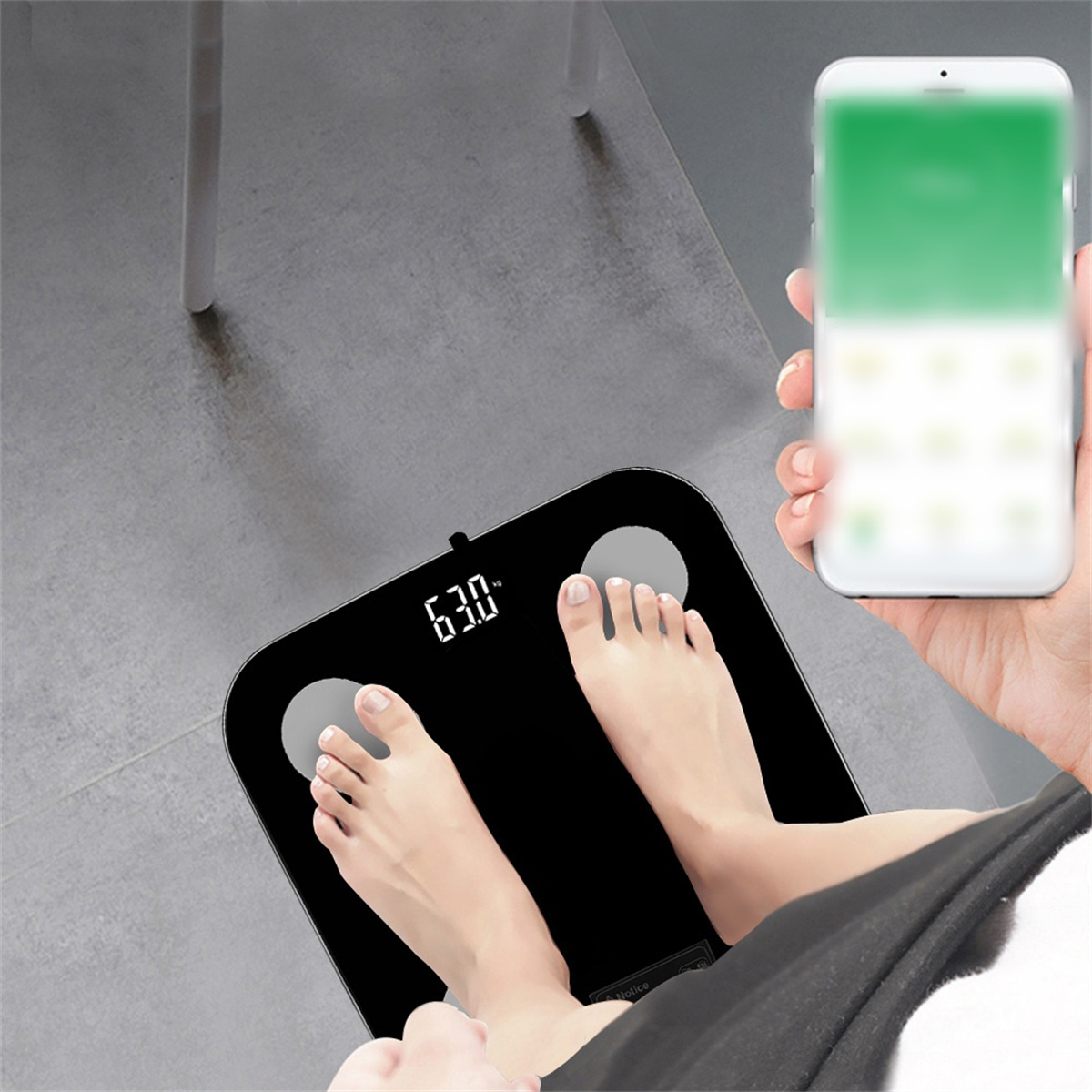 Person steht auf einer schwarzen Waage, Telefon in der Hand. Waage zeigt 63,0. Der Bildschirm ist unscharf.
