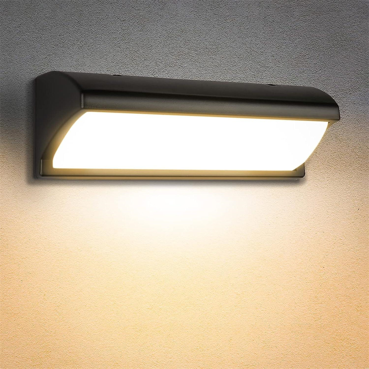 Schwarze, rechteckige Außenwandleuchte, an einer grauen Wand montiert. Das Licht ist an und scheint nach unten.