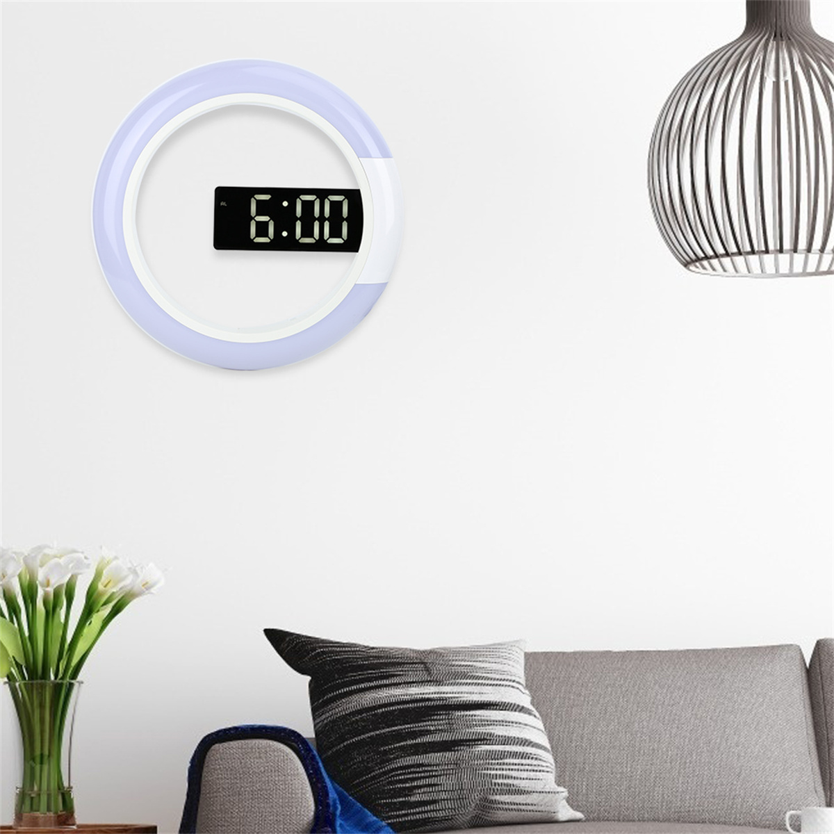 Wanddigitaluhr um 6:00 Uhr, umgeben von einem weißen Leuchtring. Ein Sofa, Blumen und eine Lampe.