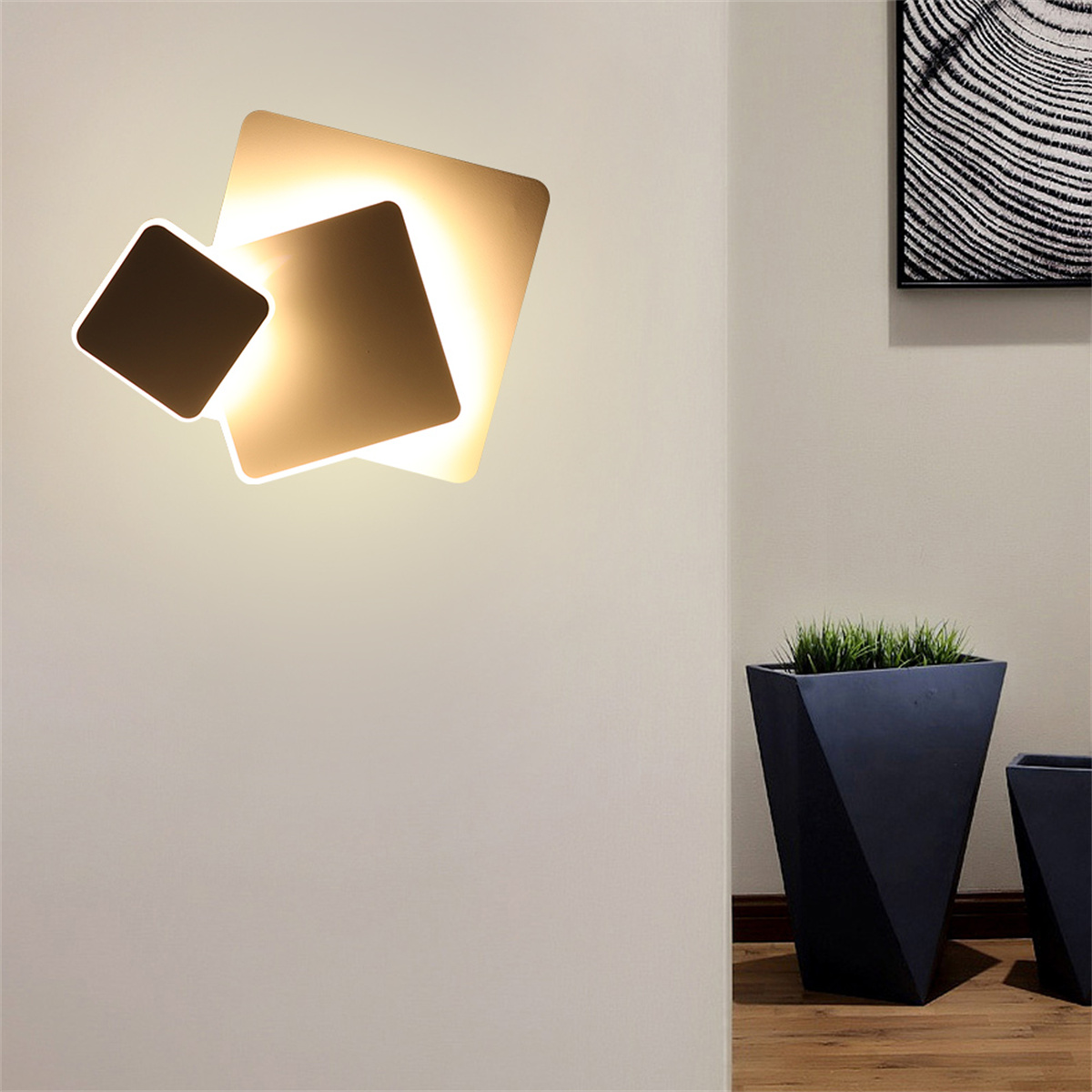 Eine Wandlampe mit drei beleuchteten quadratischen Formen, darunter zwei schwarze Blumentöpfe.