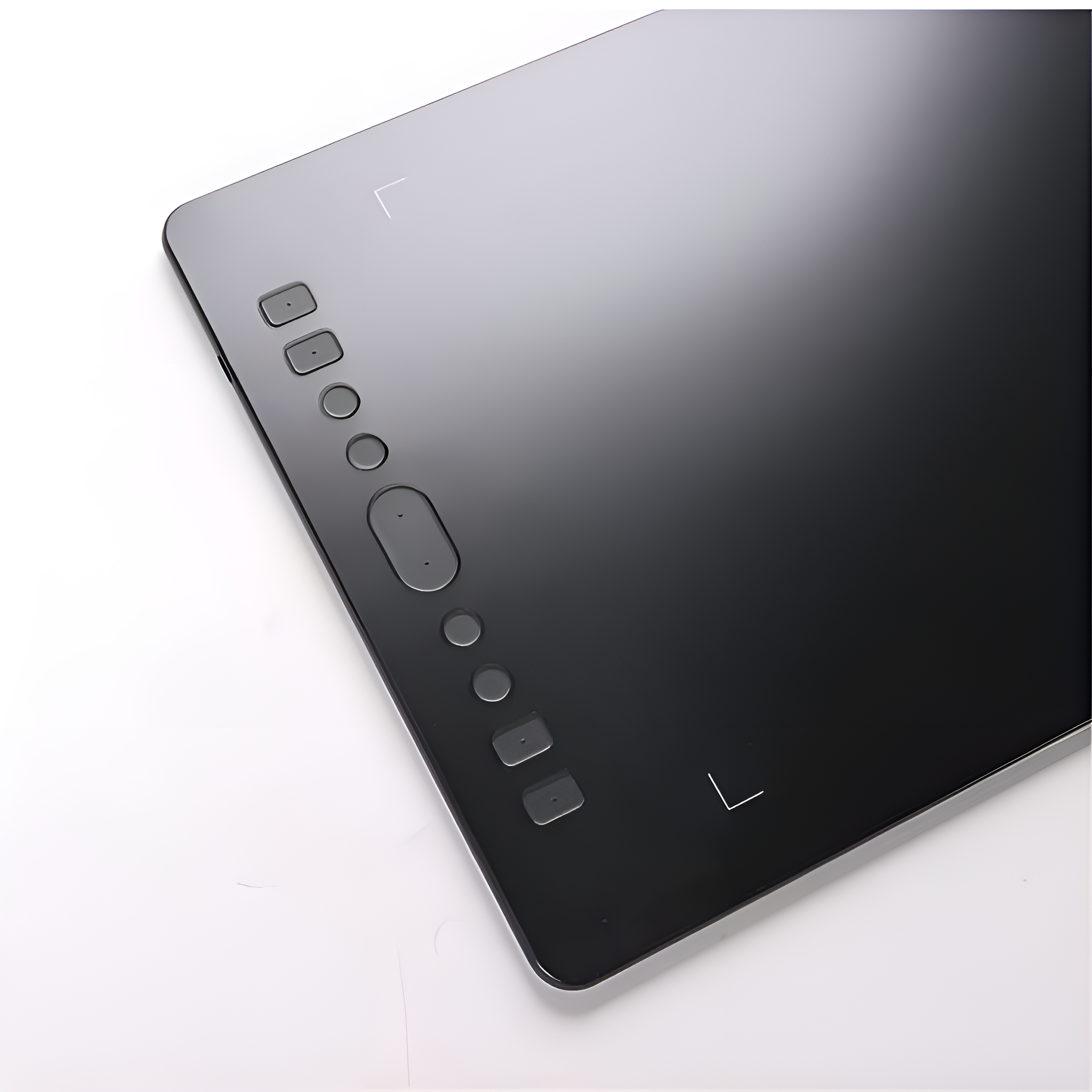 Ein schwarzes digitales Zeichentablett mit Knöpfen auf einer weißen Oberfläche. Zeigt eine reflektierende Oberfläche.