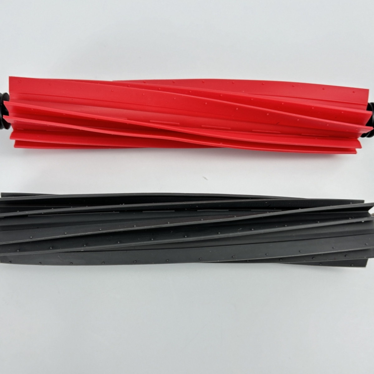 Dwie szczotki do odkurzacza, jedna czerwona, druga czarna, obie z żebrowanymi powierzchniami.