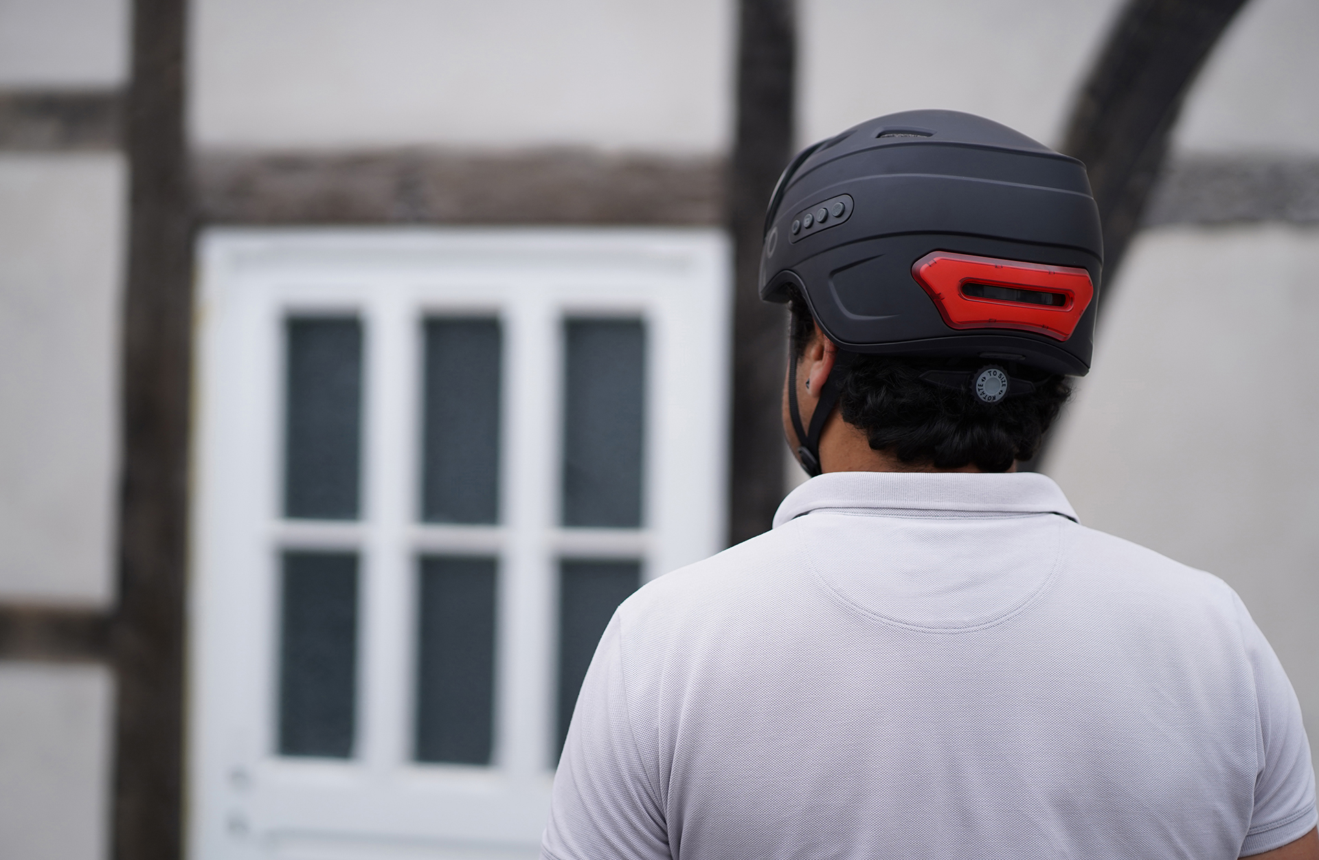 Person trägt schwarzen Helm mit rotem Licht, von hinten gesehen.