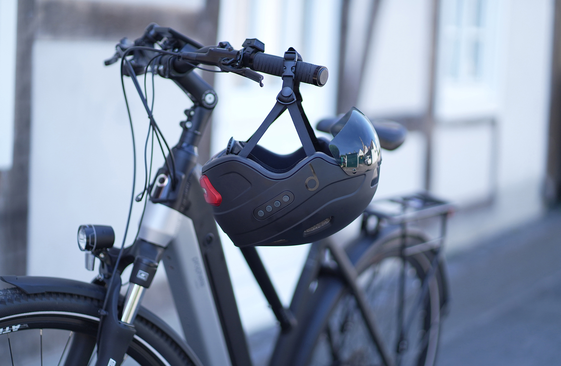 Schwarzes Fahrrad mit schwarzem Helm am Lenker. Ein weißes Gebäude im Hintergrund.