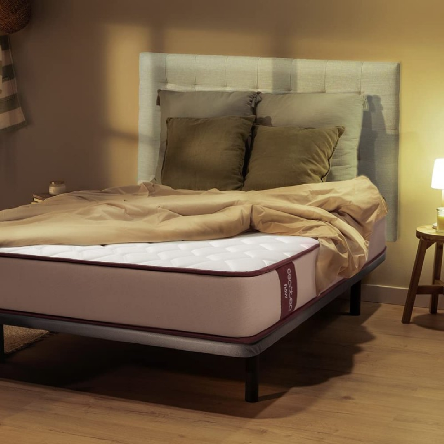 Een bed met een matras, kussens, een deken en een hoofdbord in een slaapkamer.