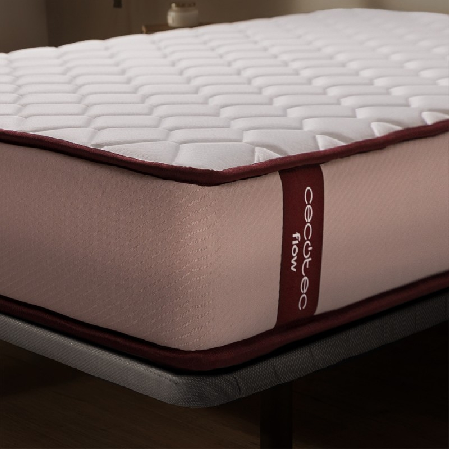 Primer plano de un colchón con borde rojo y texto Cecotec Flow. El colchón está sobre un marco.