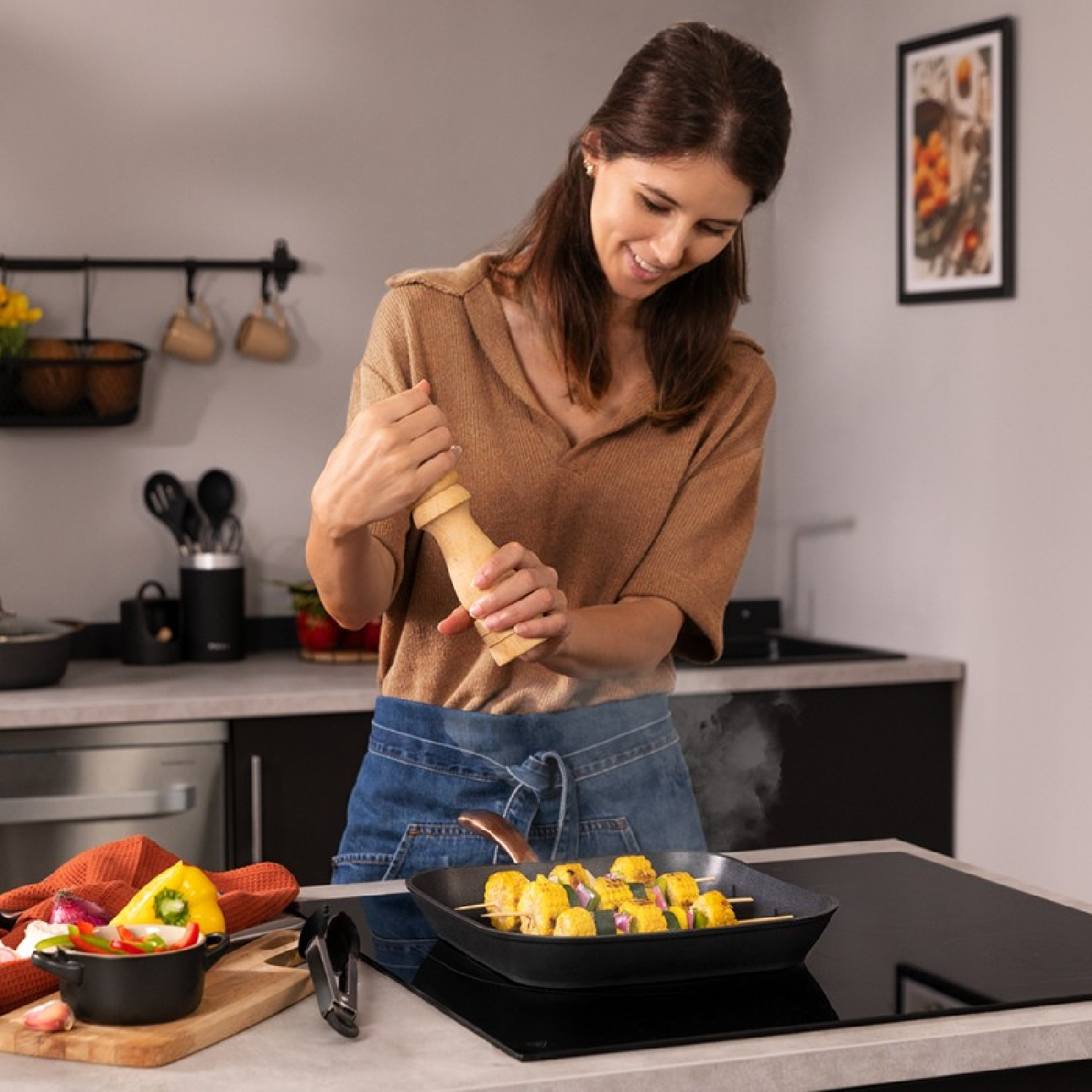 Kobieta gotuje, mieli pieprz na szaszłyki z jedzeniem na patelni na kuchence.