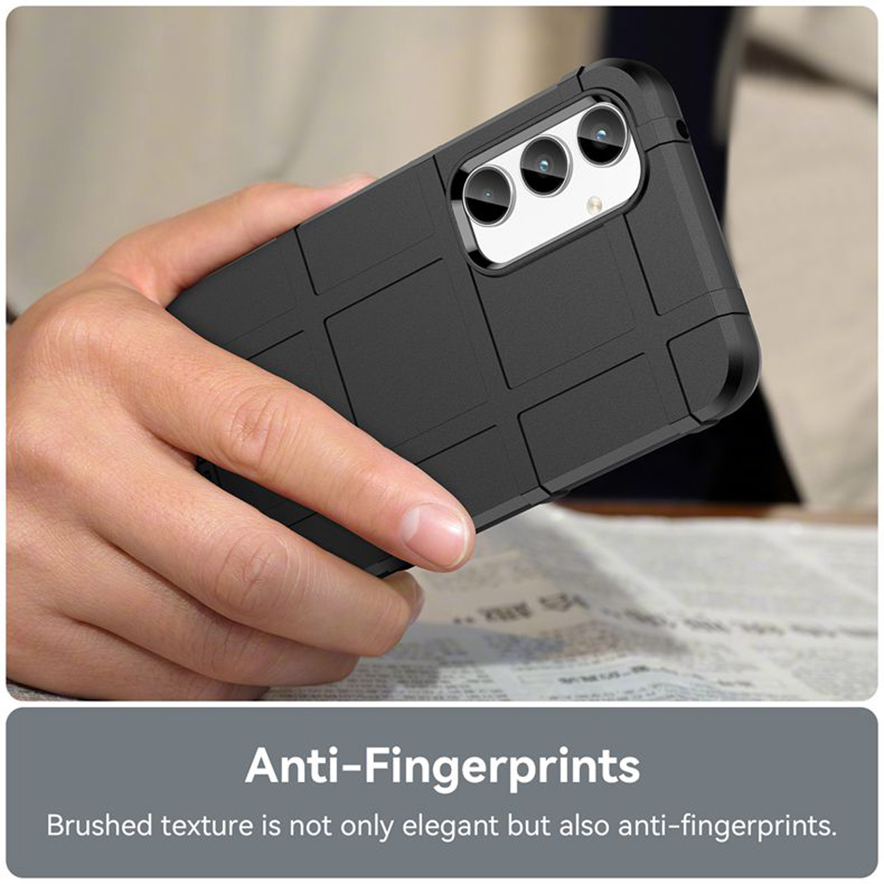 Hand houdt een zwarte telefoonhoes met een getextureerd oppervlak, op een krant, anti-vingerafdrukontwerp.