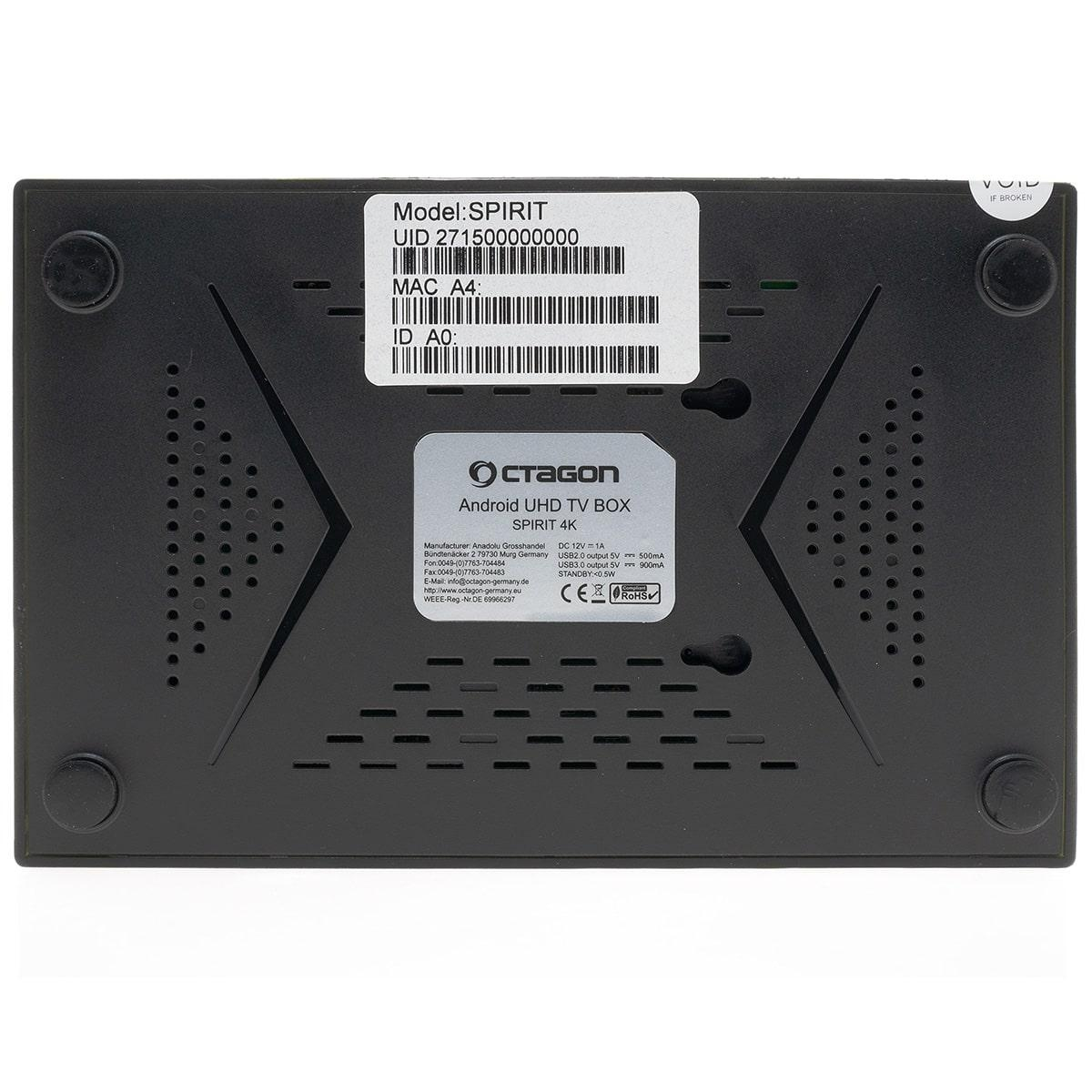 Schwarze, rechteckige Android-TV-Box mit Etiketten auf der Rückseite und vier schwarzen Gummifüßen.