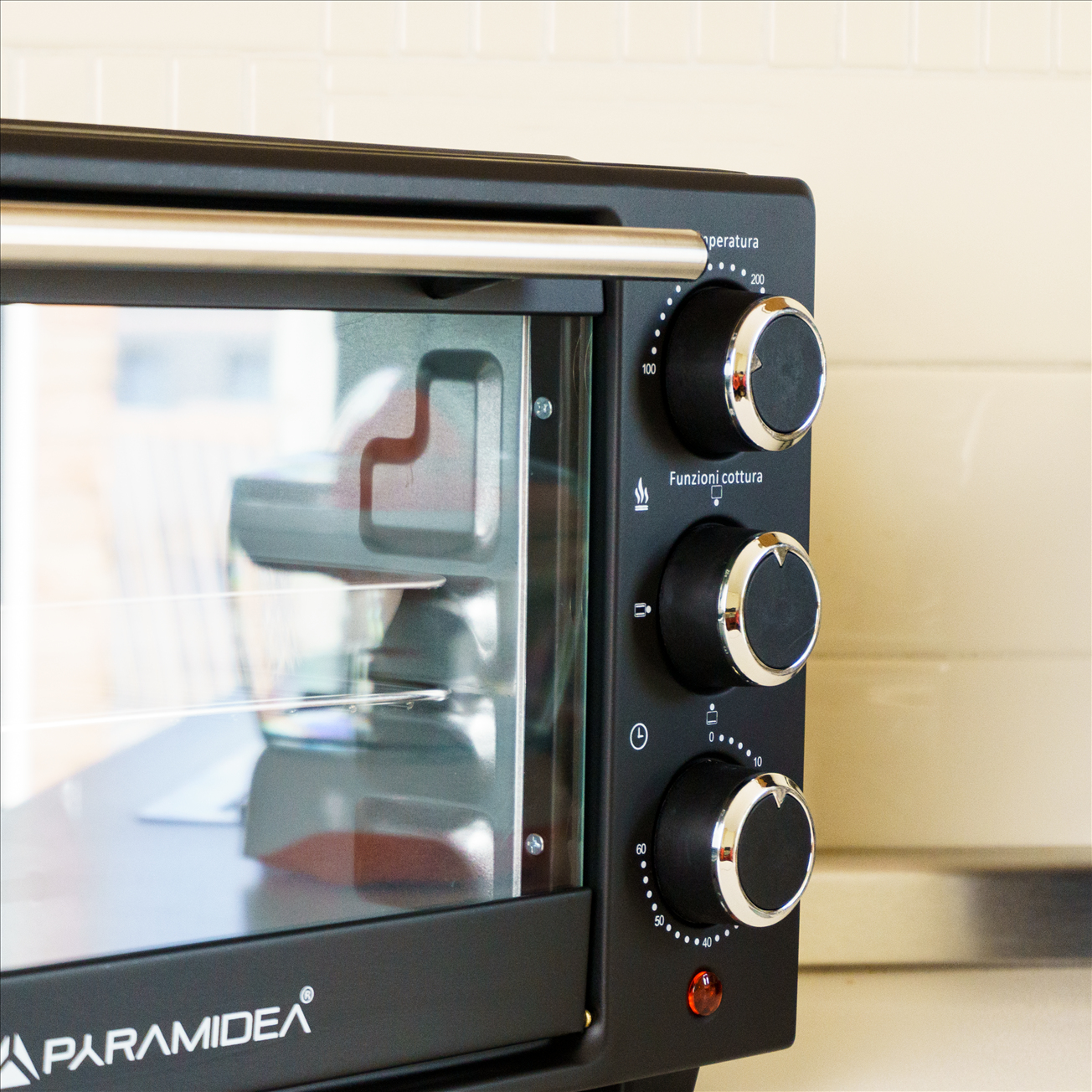 Primo piano di un forno nero con manopole e porta a vetri.