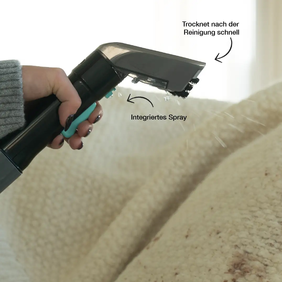 Eine Hand besprüht ein weißes Objekt. Text: Integriertes Spray, Trocknet nach der Reinigung schnell. Objekt auf Teppich.