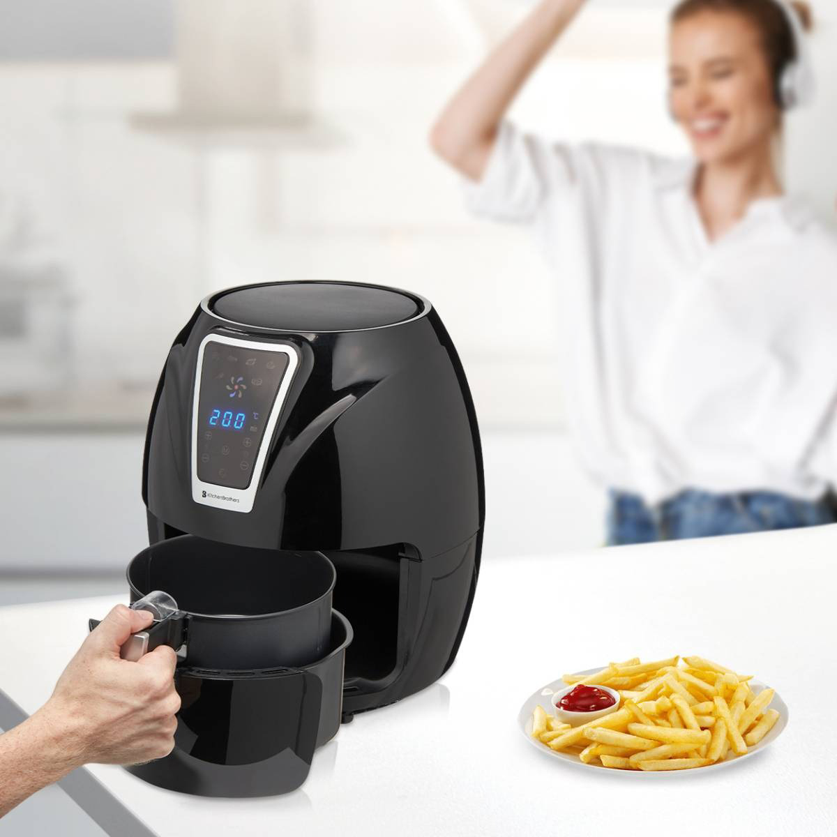 Zwarte airfryer met friet, persoon op de achtergrond danst.