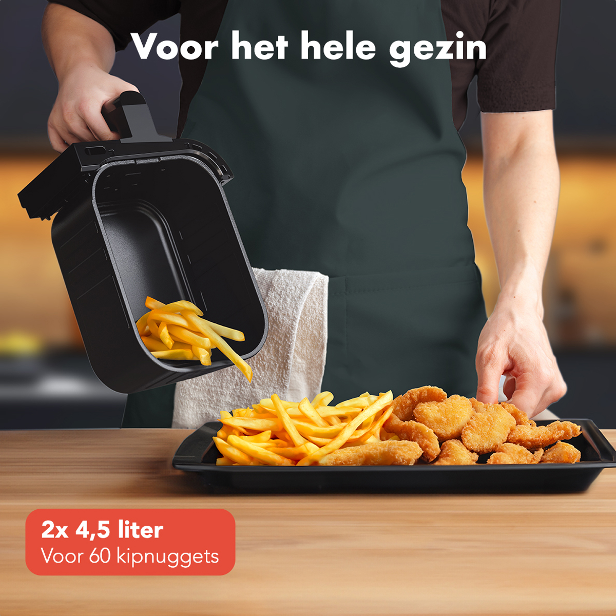 Someone pouring fries and chicken nuggets from an air fryer. They are on a black tray on a table.
