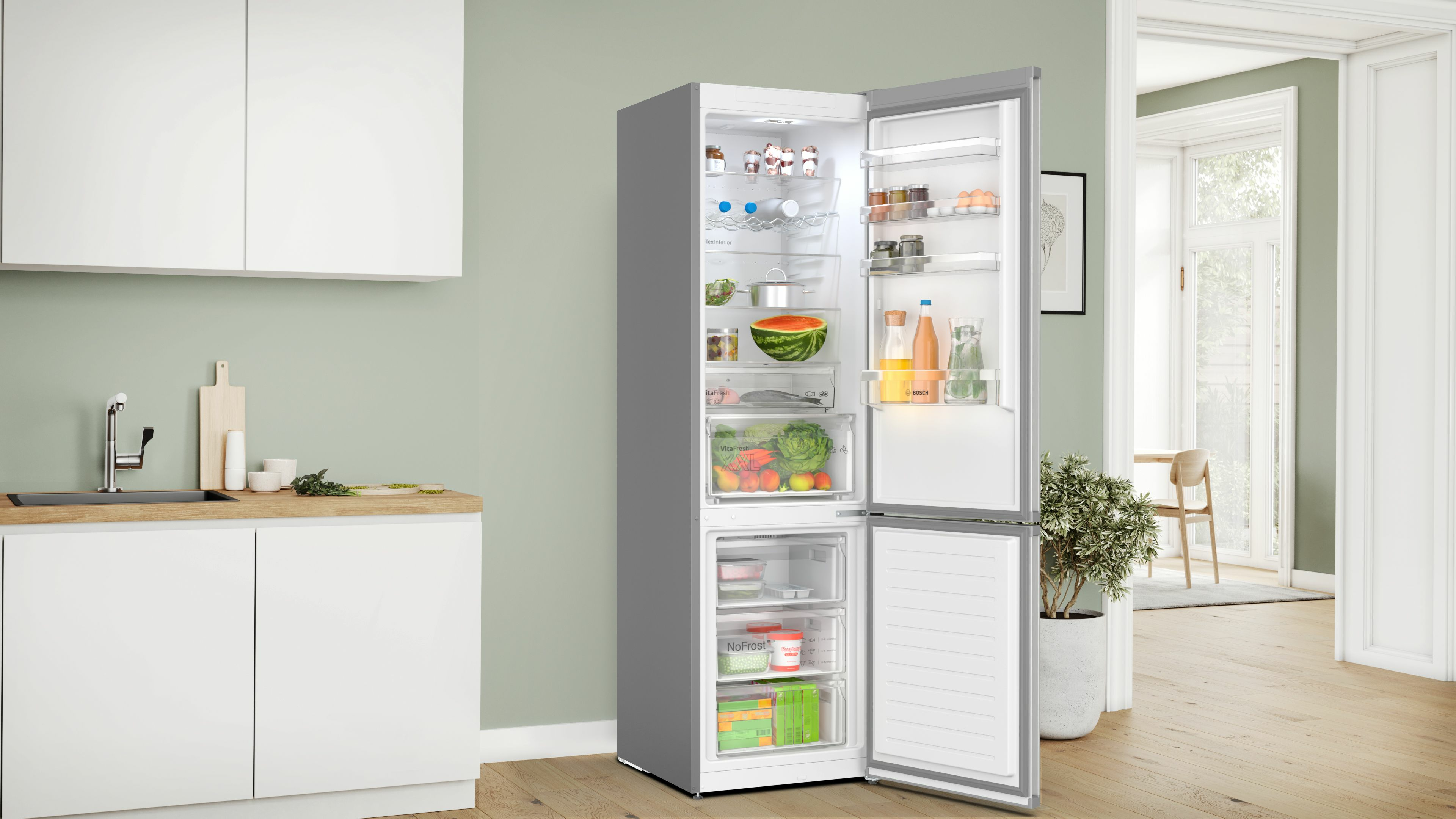 Frigorifero aperto con alimenti: anguria, bottiglie, verdure e cassetto congelatore.
