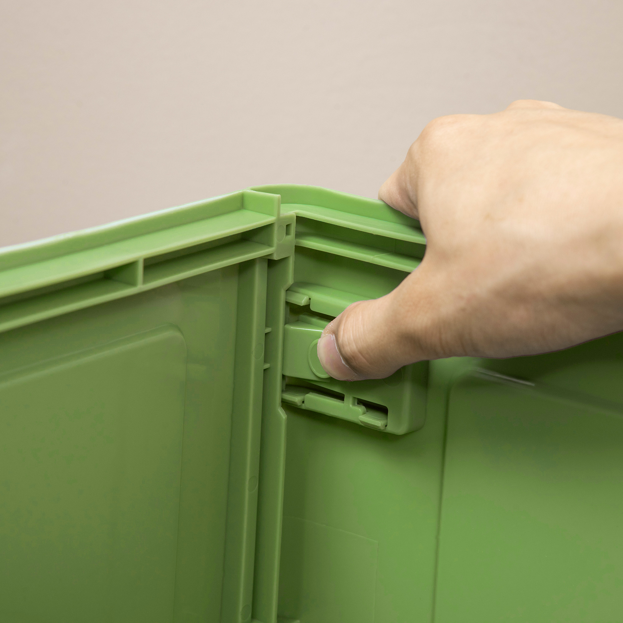 Una mano preme una clip verde su un contenitore di plastica.