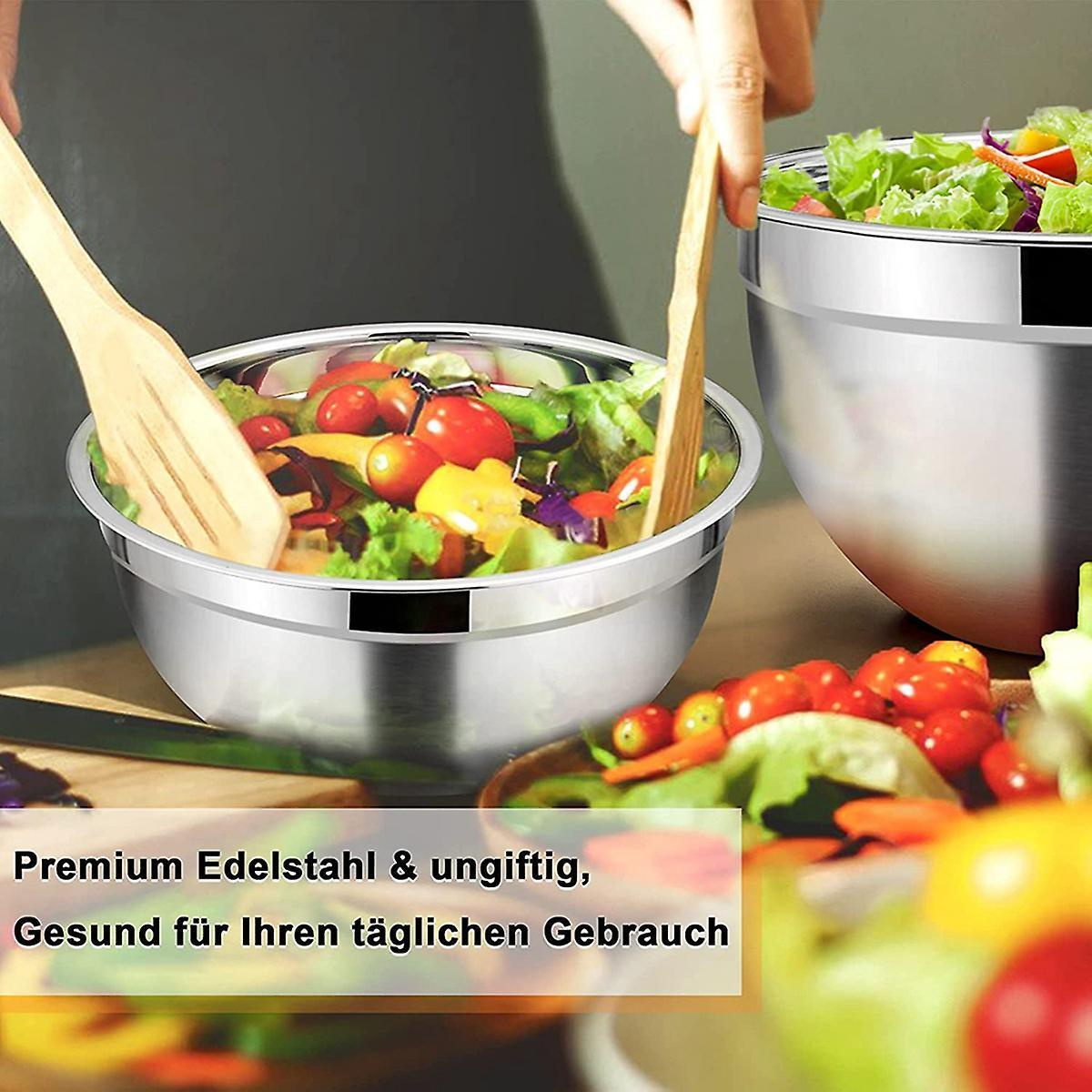 Edelstahl-Rührschüsseln. Holzspatel und Salat sind in den Schüsseln.