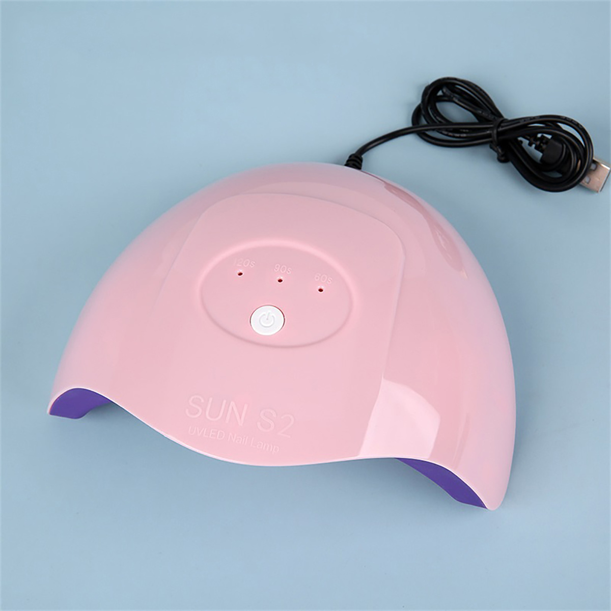 Eine rosa UV-LED-Nagellampe mit Knöpfen und Netzkabel auf hellblauem Untergrund.