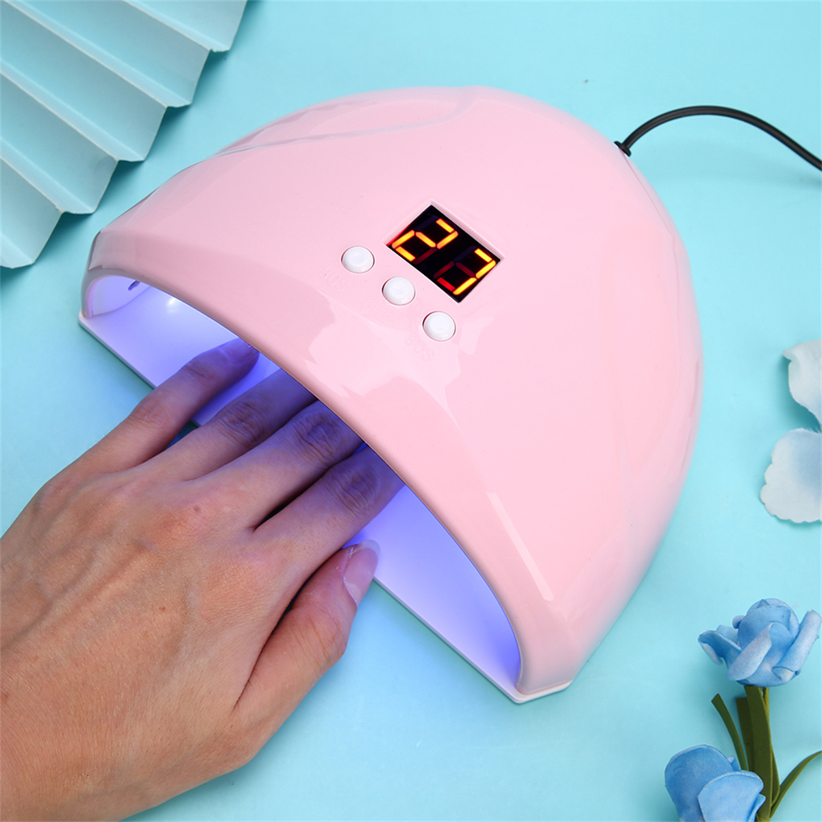 Pinke Nagellampe mit Hand darin. Anzeige zeigt Timer. Blauer Hintergrund.