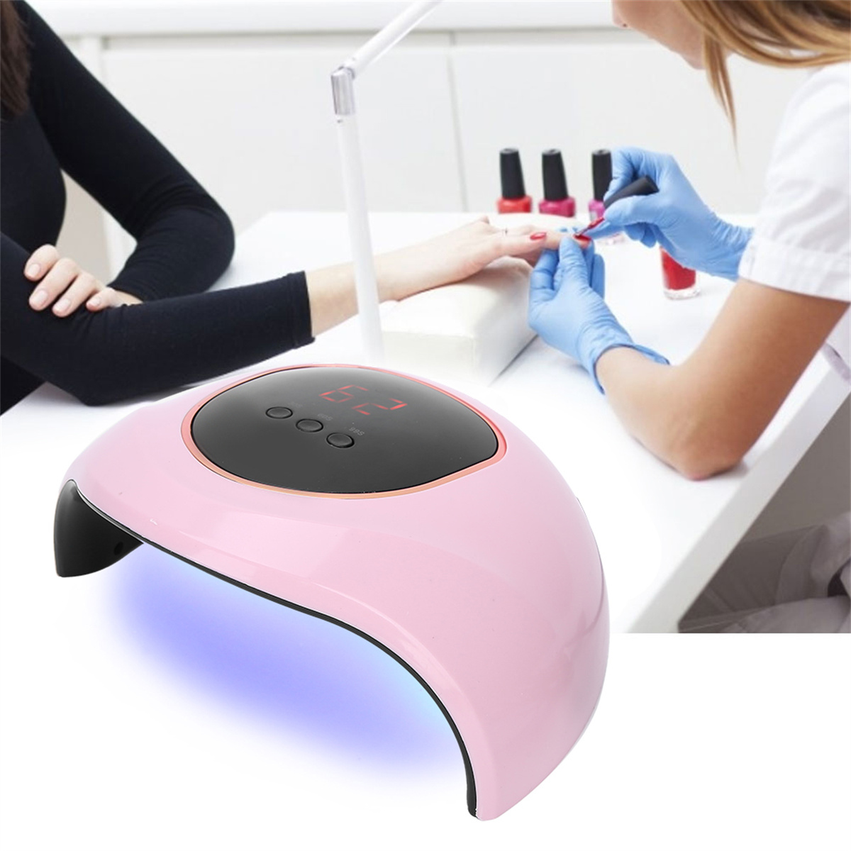 Rosafarbene Nagellampe mit einer Frau, die Nägel macht. Die Lampe ist über der Hand einer Frau. Ein Display ist an.