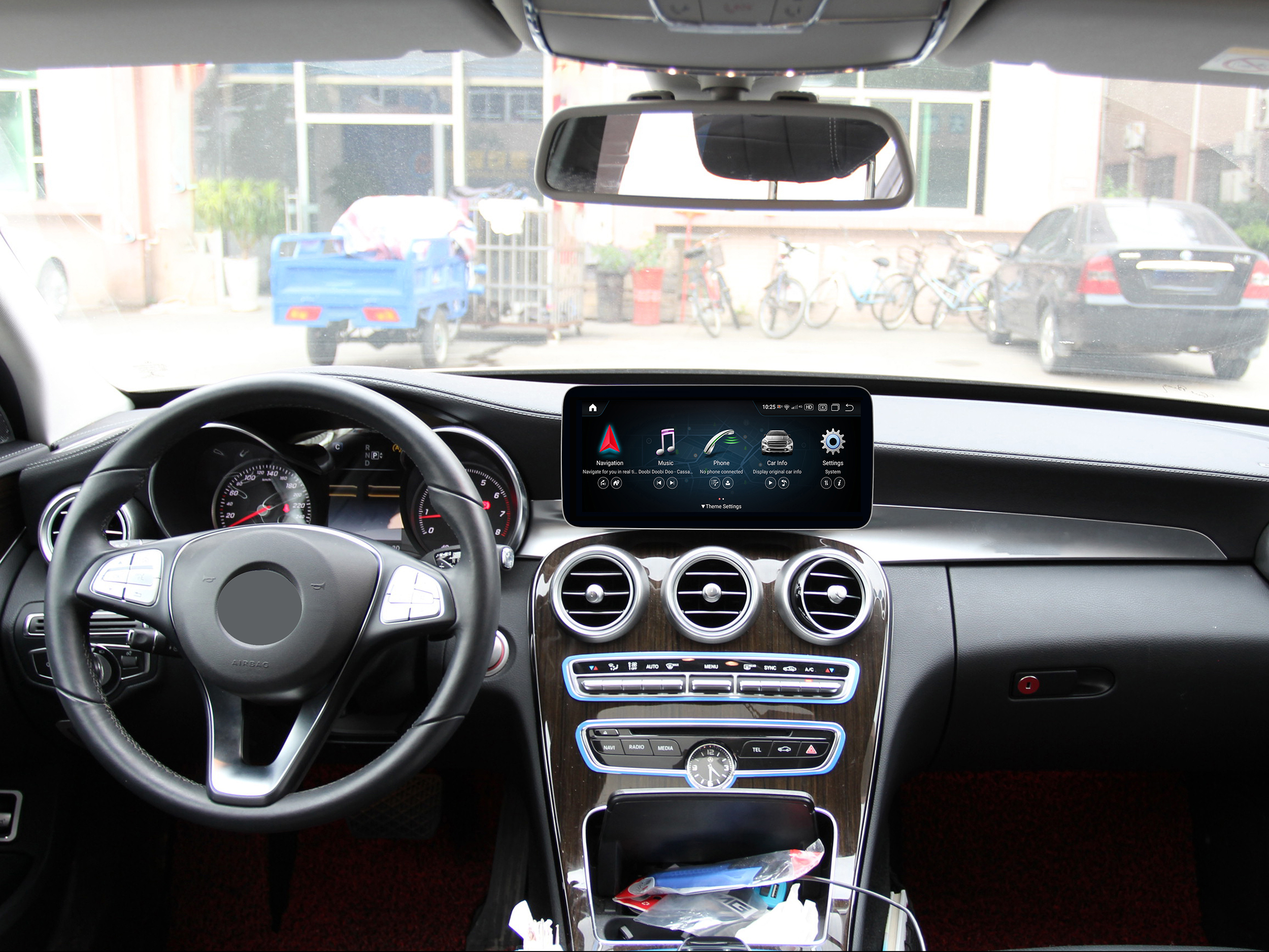 Ein Auto-Armaturenbrett mit einem Bildschirm, der Navigation und andere Optionen anzeigt, Lenkrad und Lüftungsschlitze.