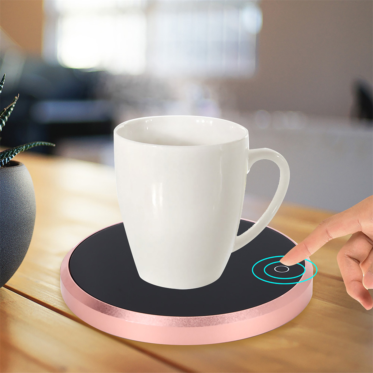 Ein weißer Becher auf einem roségoldenen Wärmer, Dampf steigt auf. Ein Finger berührt den Knopf.