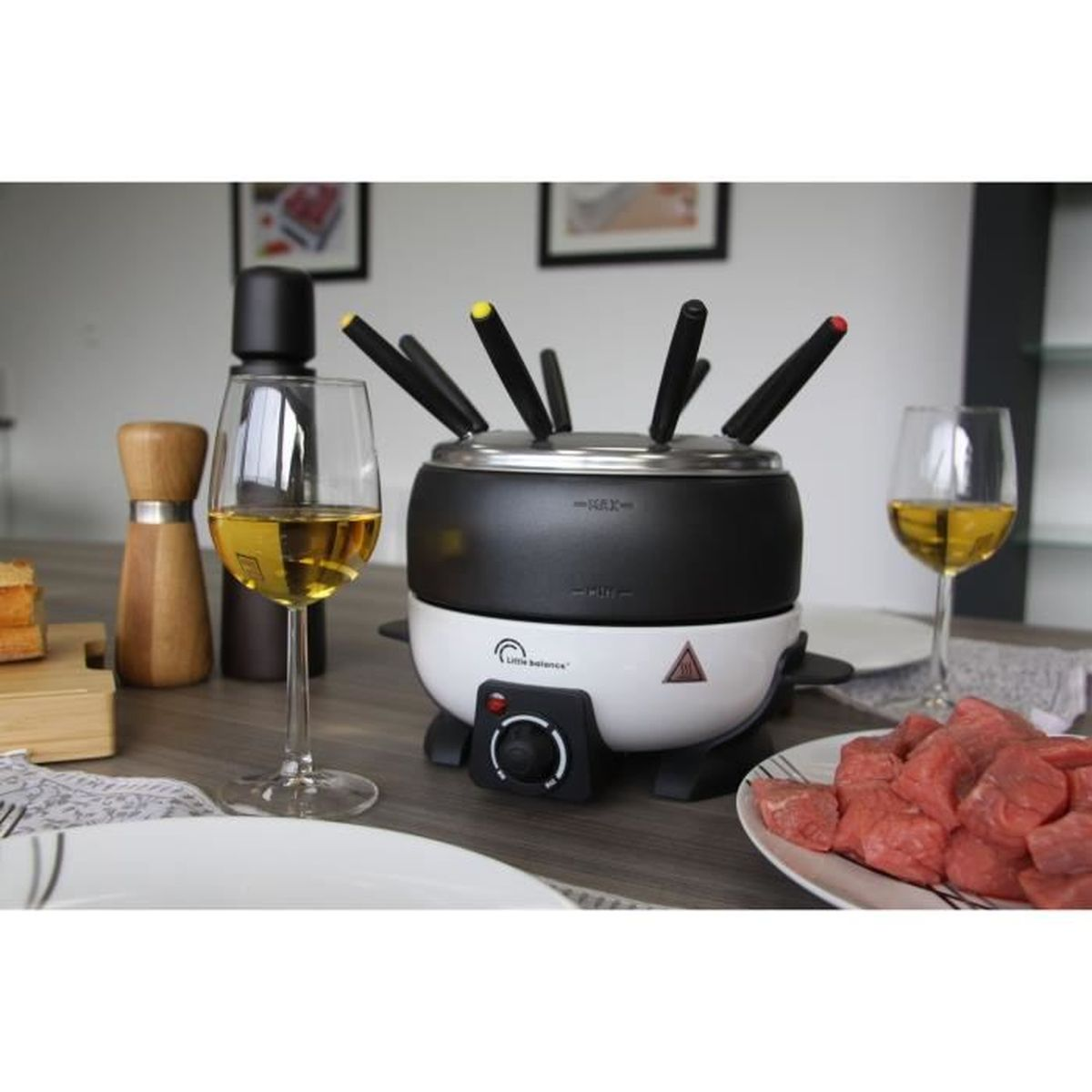 Un set da fonduta con cubetti di carne, vino e macina spezie.