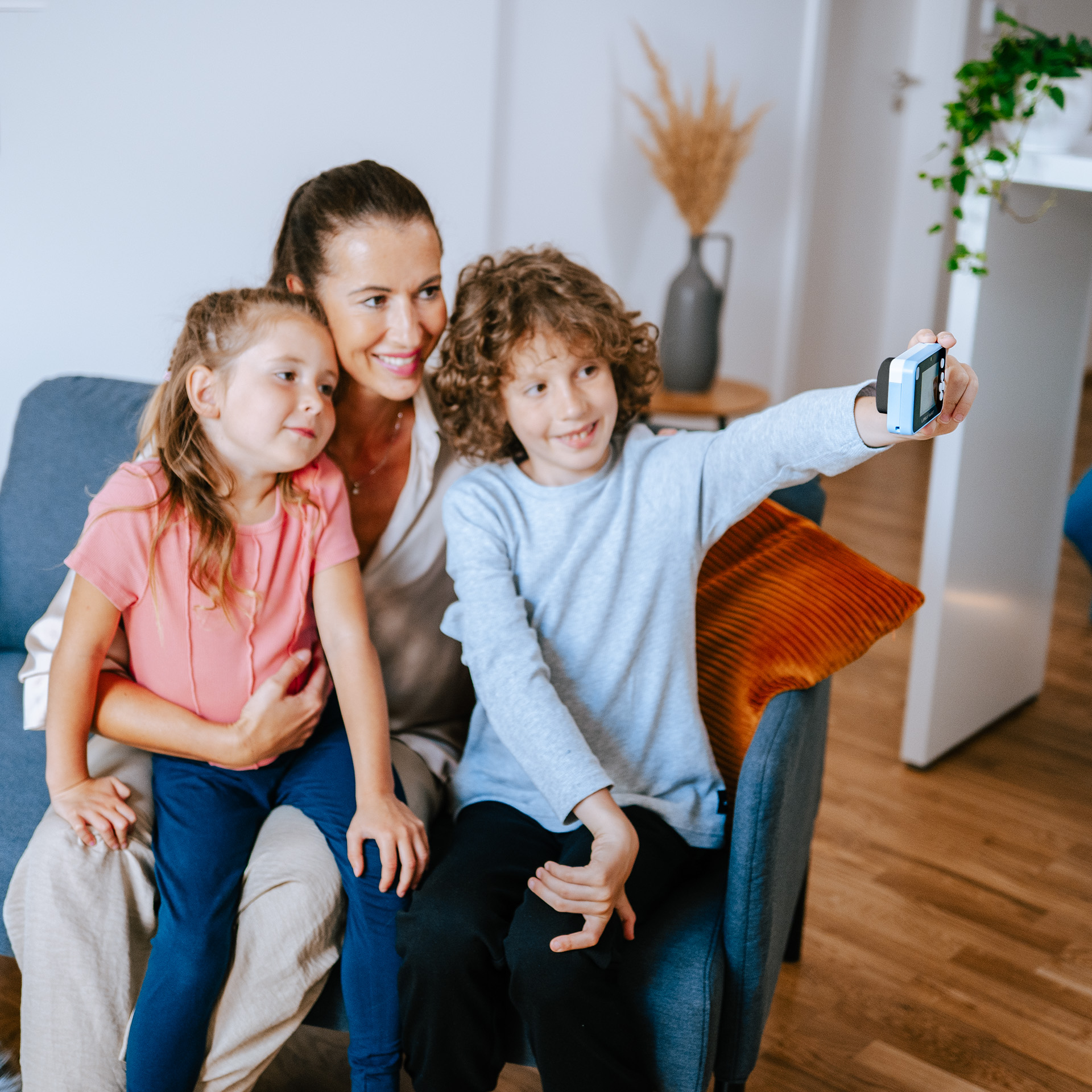 Frau, Kind und Junge machen ein Selfie mit einer blauen Smartwatch.