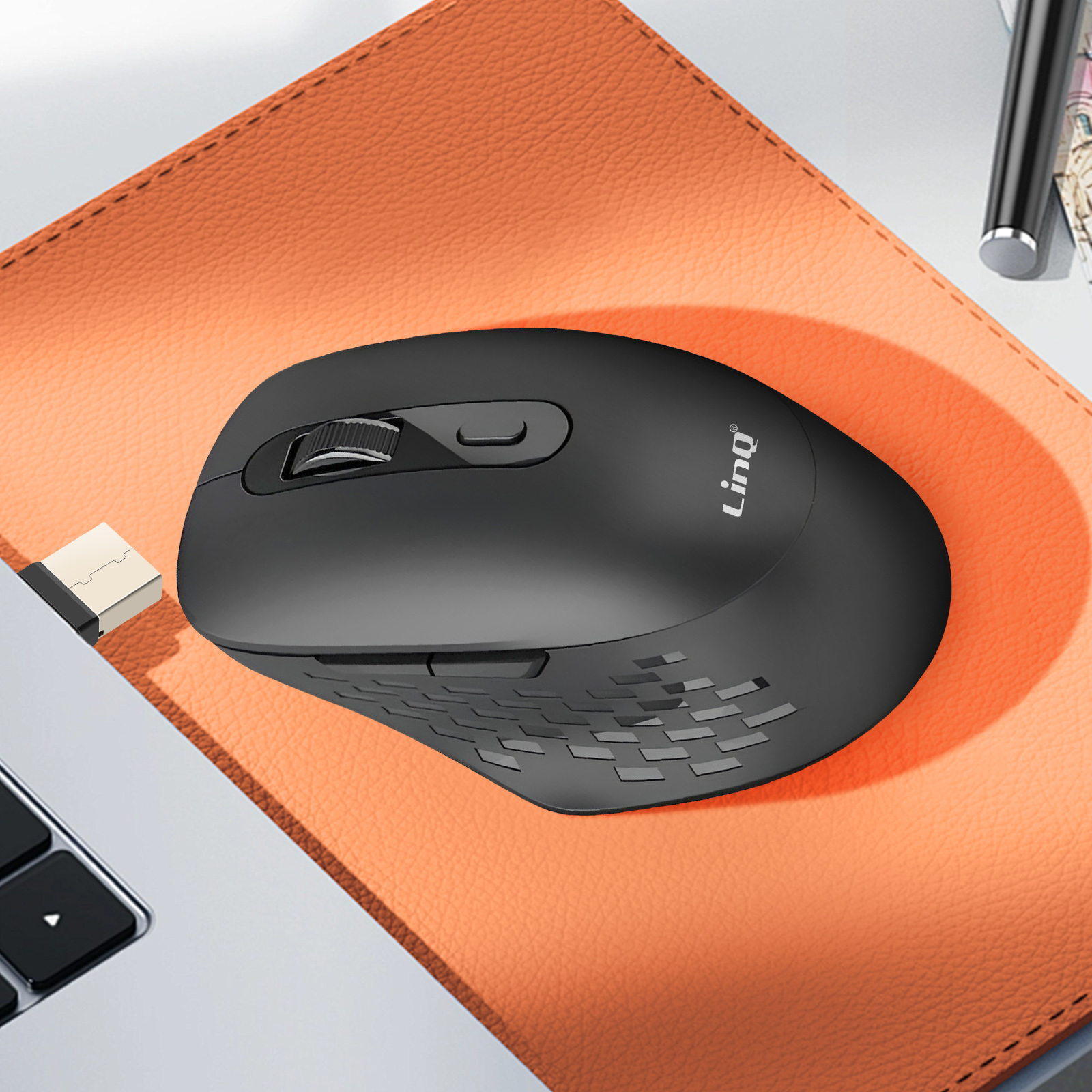 Mouse wireless nero su tappetino arancione. Ricevitore USB collegato a un laptop.