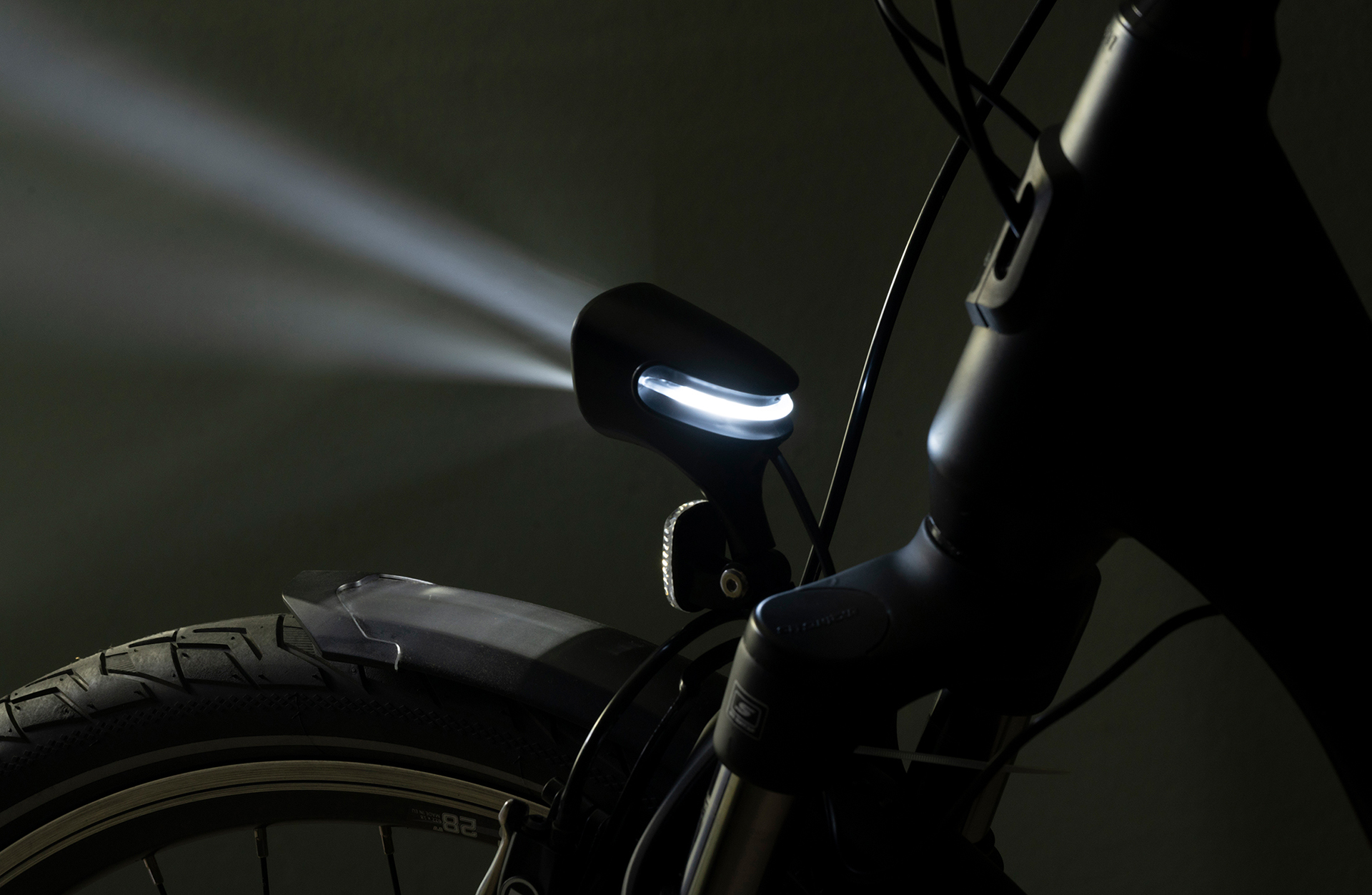 Fahrradscheinwerfer leuchtet hell. Das Vorderrad und der Kotflügel des Fahrrads sind sichtbar.