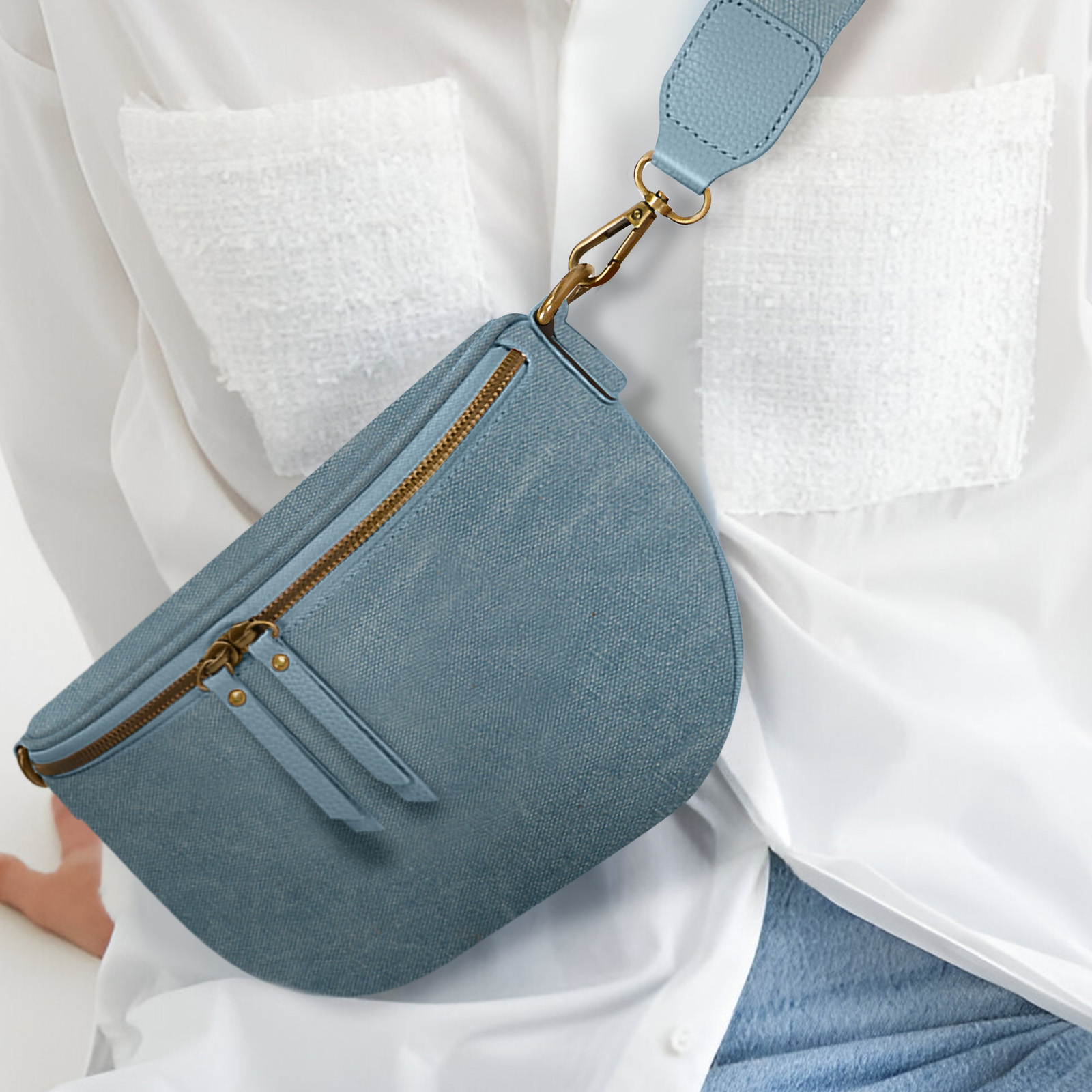 Un bolso azul con cremallera dorada, sobre una camisa blanca.