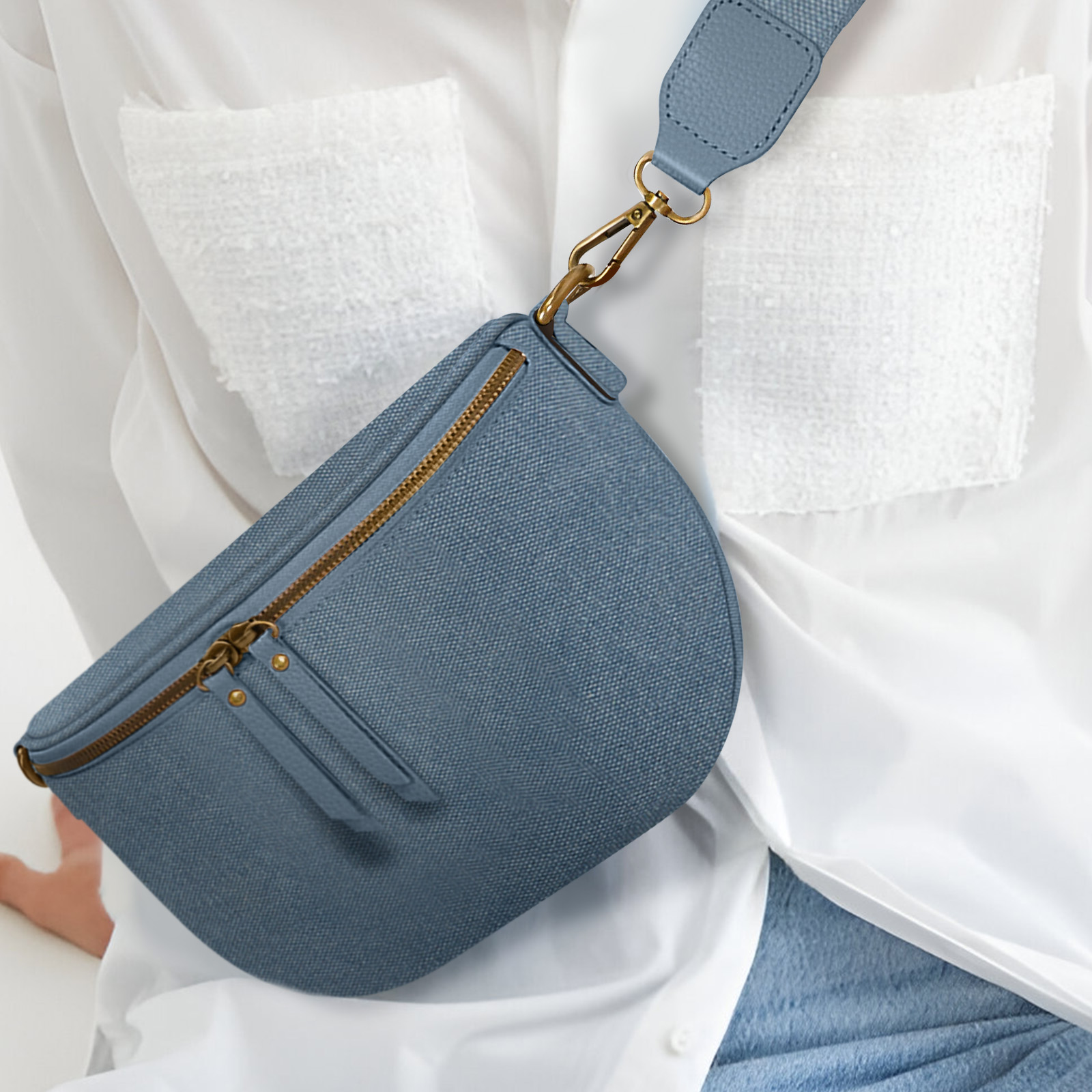 Bolso azul en forma de media luna con cremallera dorada, usado por una persona con camisa blanca.