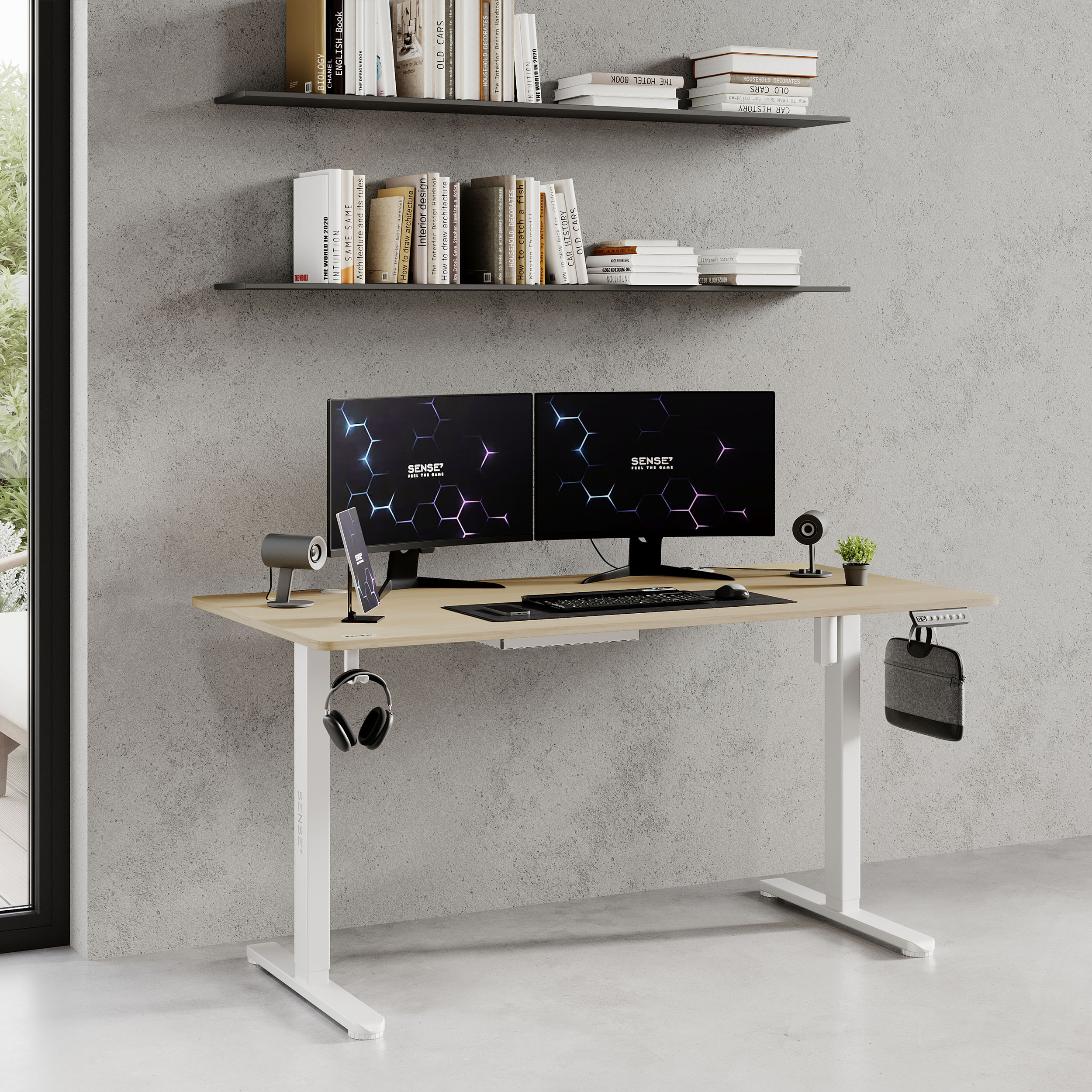 Ein Schreibtisch aus hellem Holz mit zwei Monitoren. Ein Telefon, Kopfhörer und ein Lautsprecher stehen auf dem Schreibtisch.