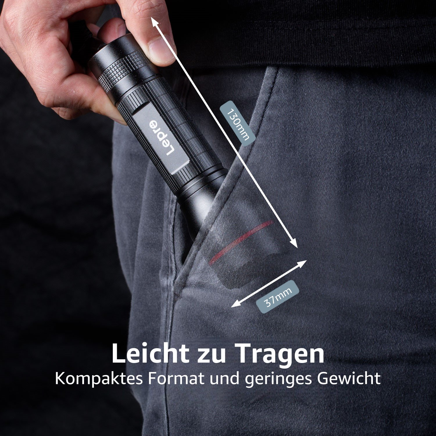 Eine schwarze Taschenlampe in einer grauen Hosentasche. Abmessungen werden mit Pfeilen angezeigt.