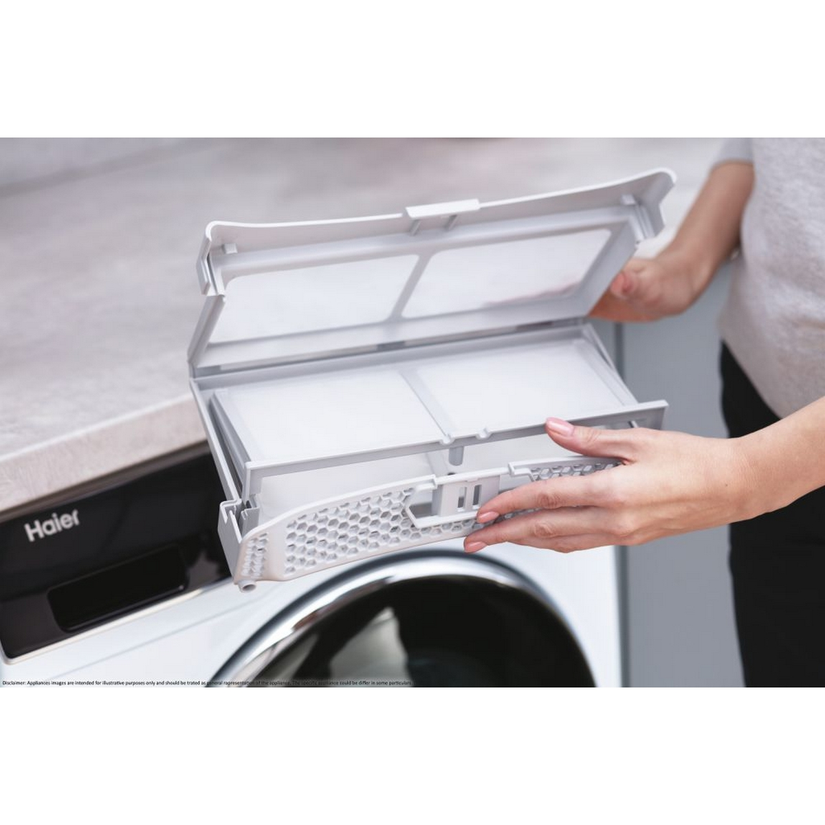 Donna che tiene un filtro bianco di un'asciugatrice Haier, vicino alla macchina.