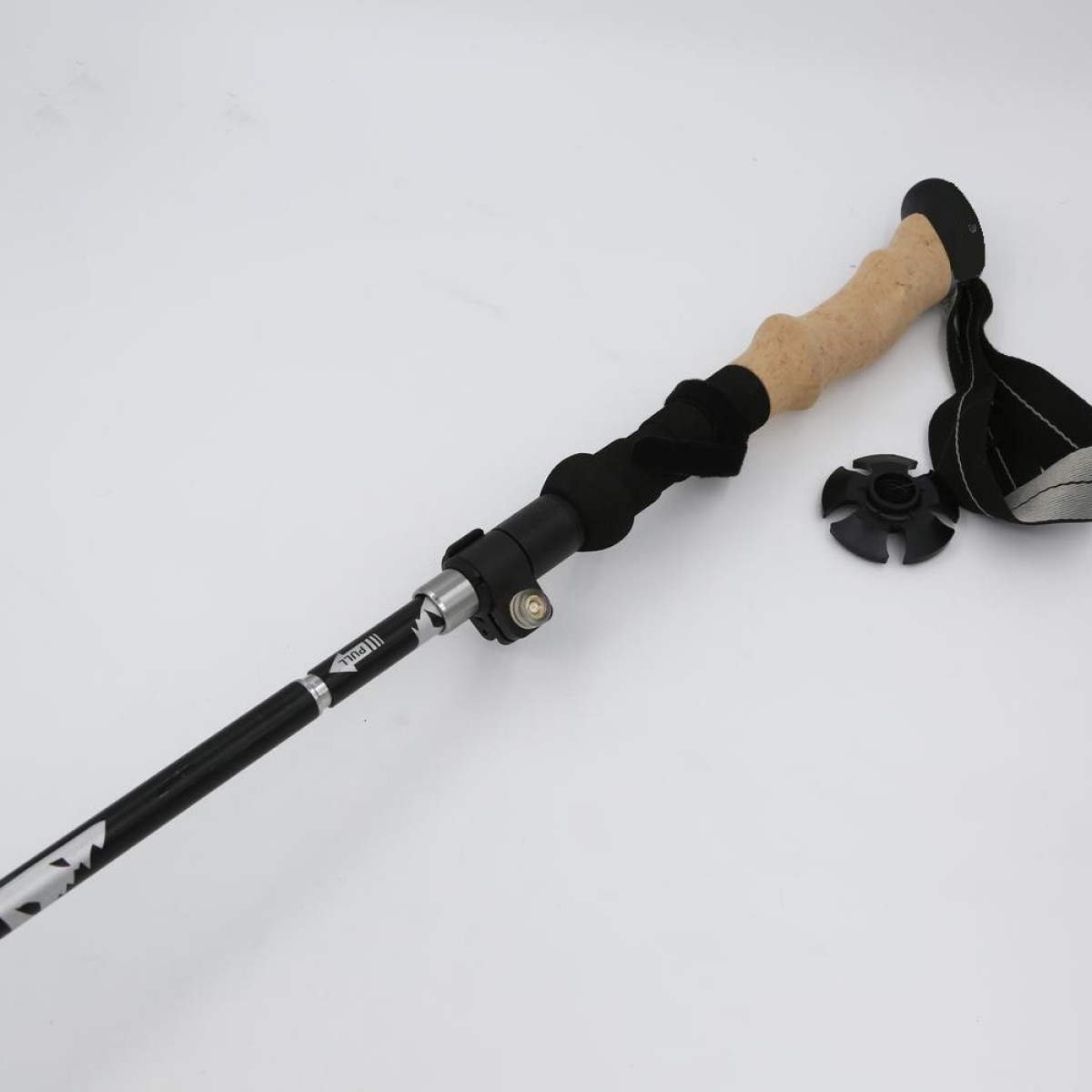 Kij trekkingowy na białym tle. Czarny i srebrny z korkową rączką.