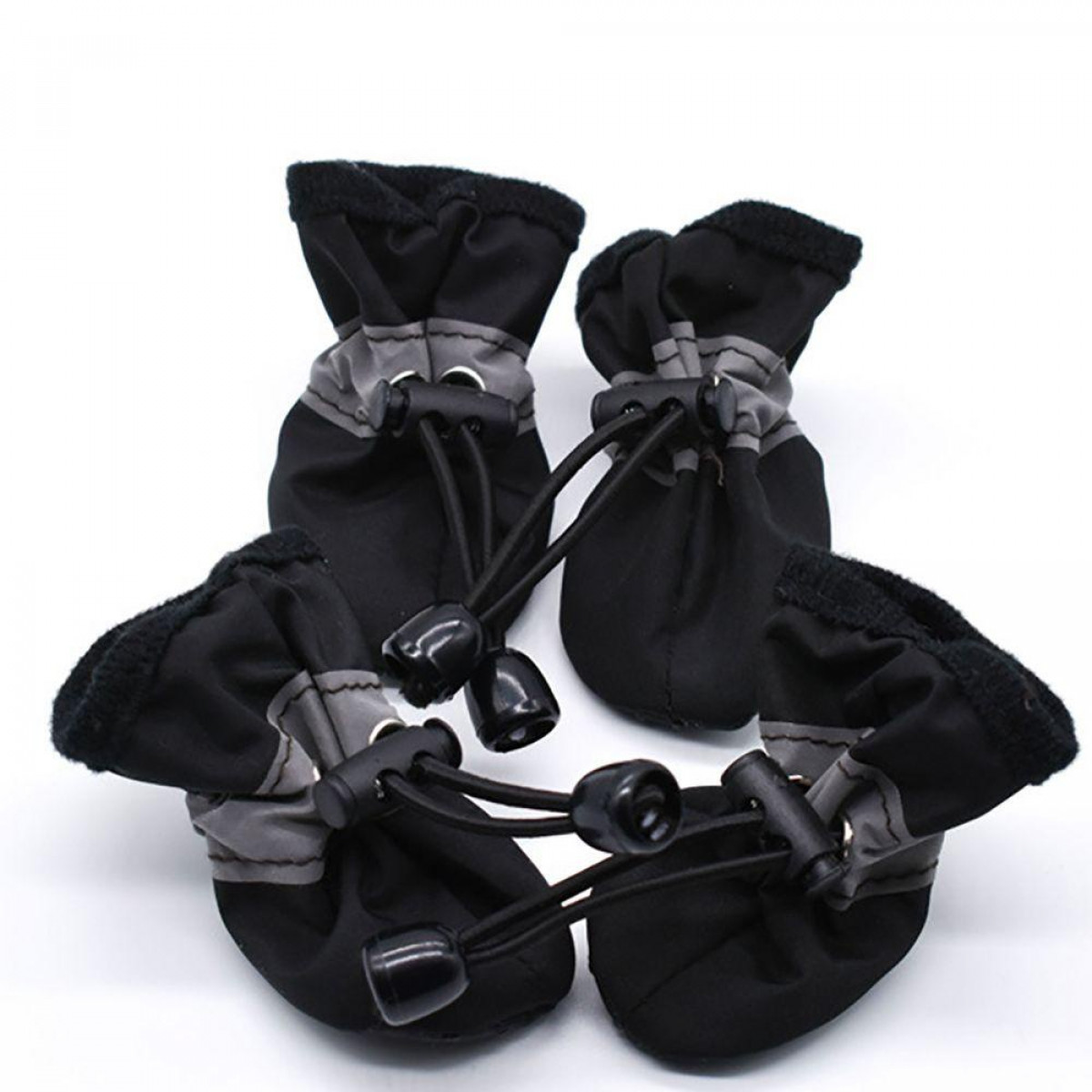 Vier kleine schwarze Hundestiefel mit grauen Akzenten, Schnürsenkel sichtbar, auf weißer Oberfläche.