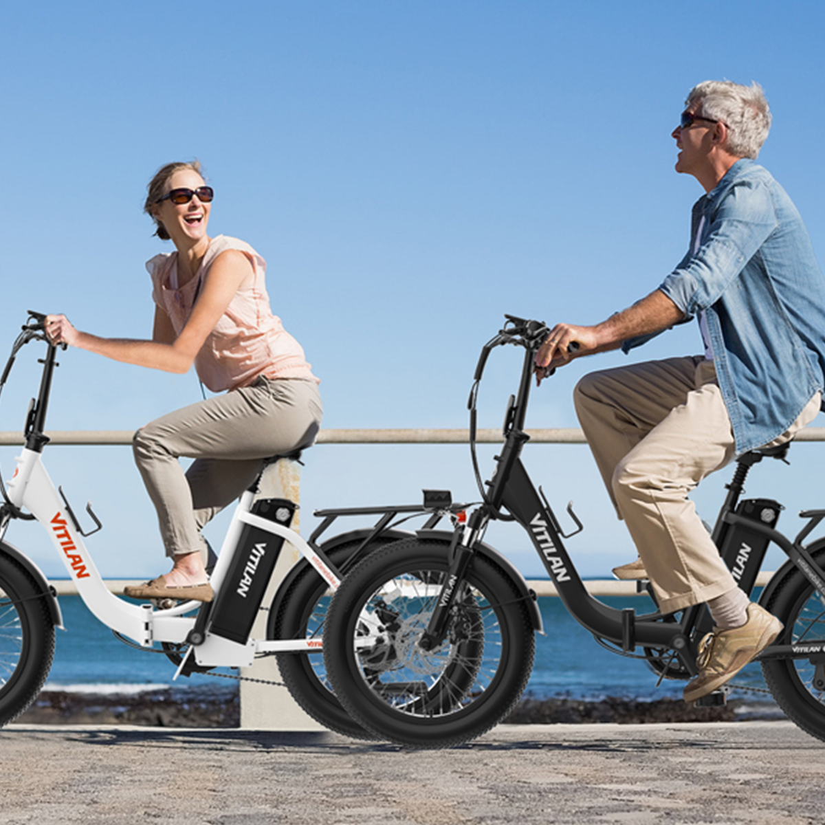 Para jeżdżąca na rowerach elektrycznych w słoneczny dzień nad morzem.